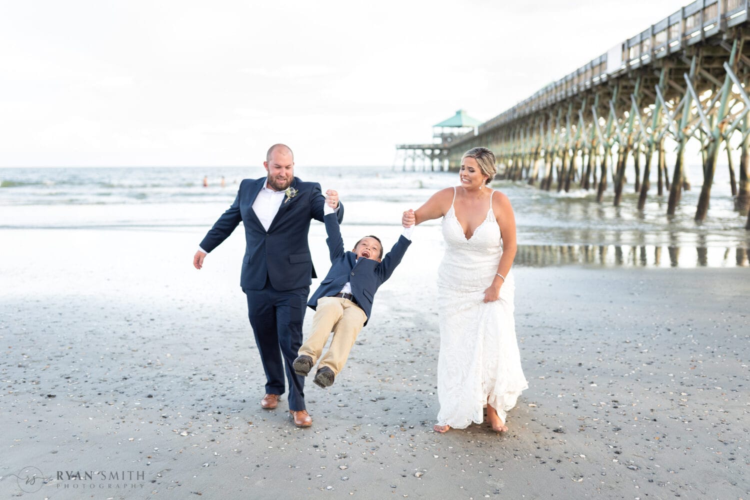 Bride and groom swinging son in the air - Folly Beach - Charleston