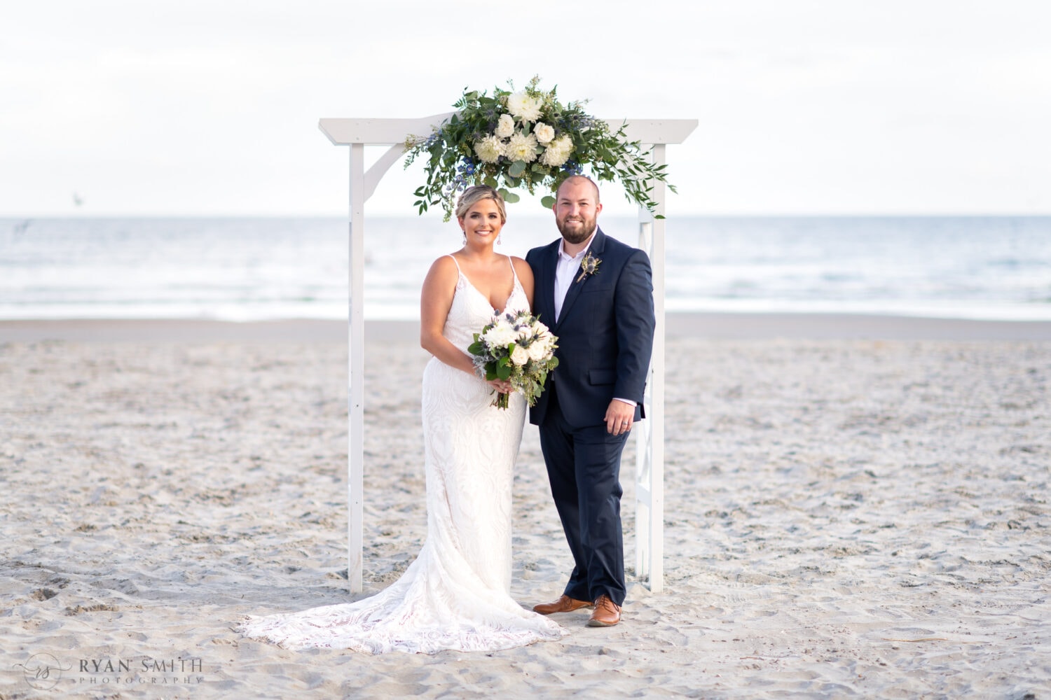 Bride and groom under the wedding arch - Folly Beach - Charleston