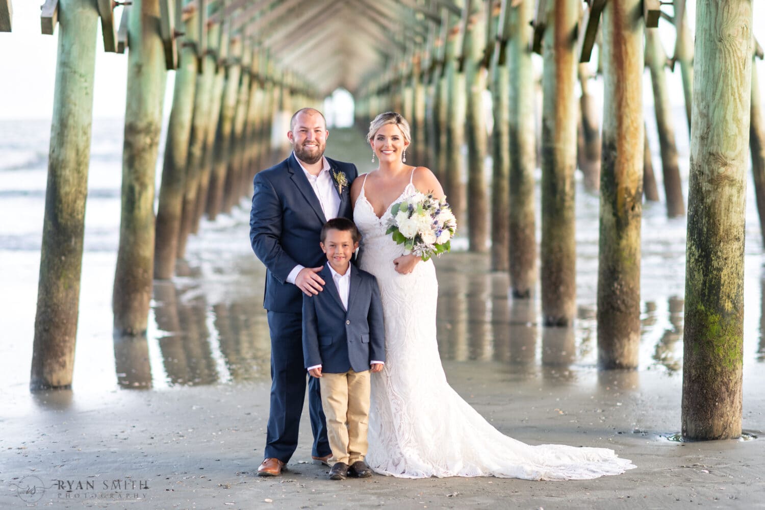 Bride and groom with son under the pier - Folly Beach - Charleston