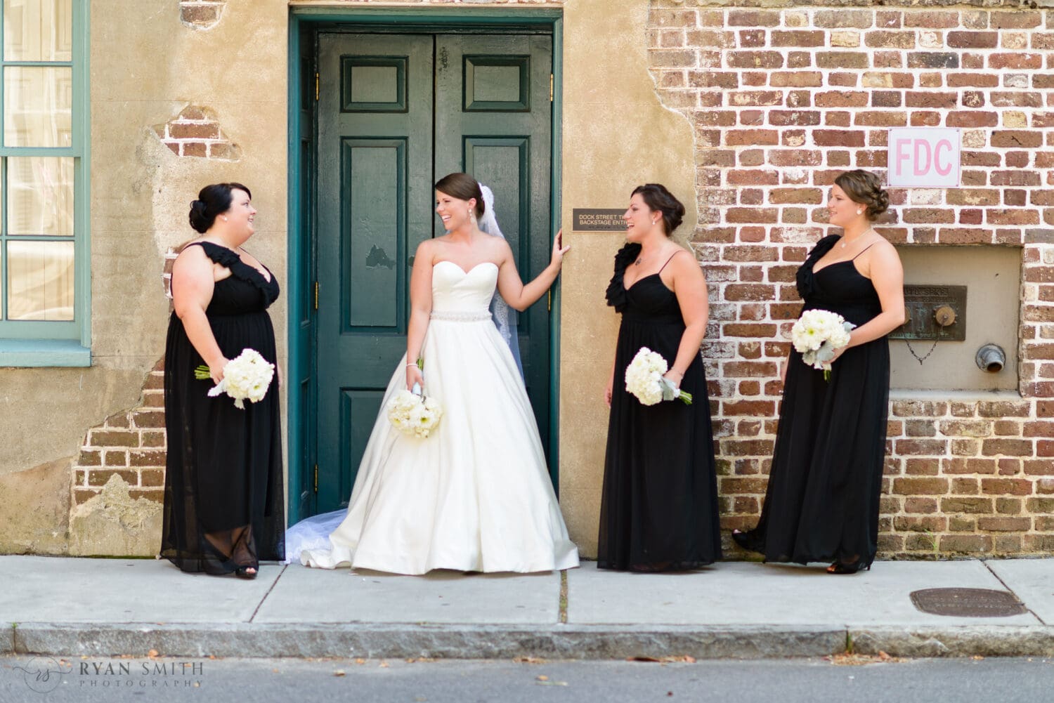 Bride laughing with bridesmaids by the brick wall - Downtown Charleston, SC