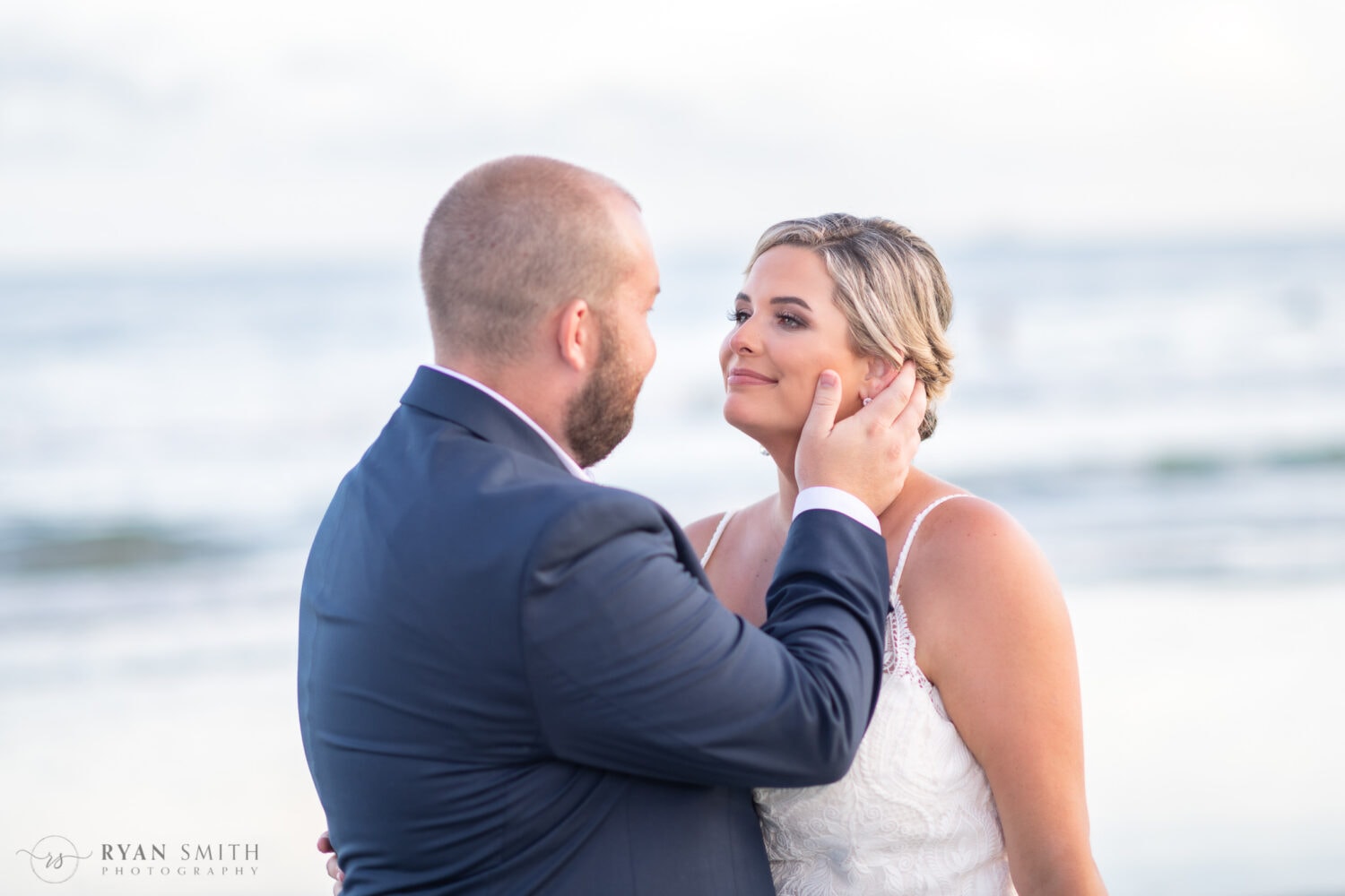 Groom touching wife's face looking into her eyes - Folly Beach - Charleston