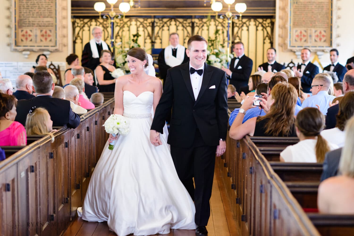 Happy bride and groom walking down the aisle together - French Huguenot Protestant Church