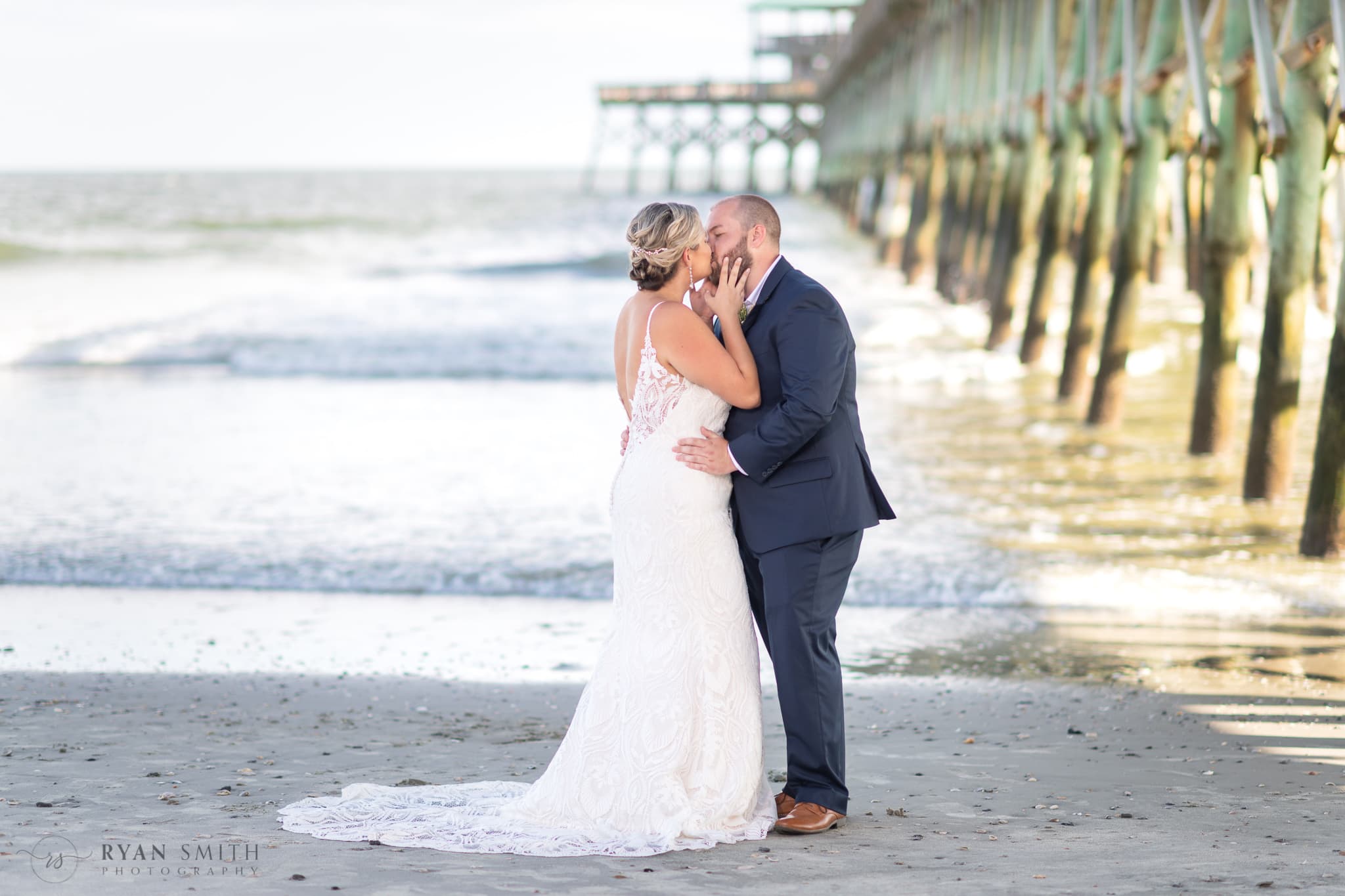 Kiss by the pier before the ceremony - Folly Beach - Charleston