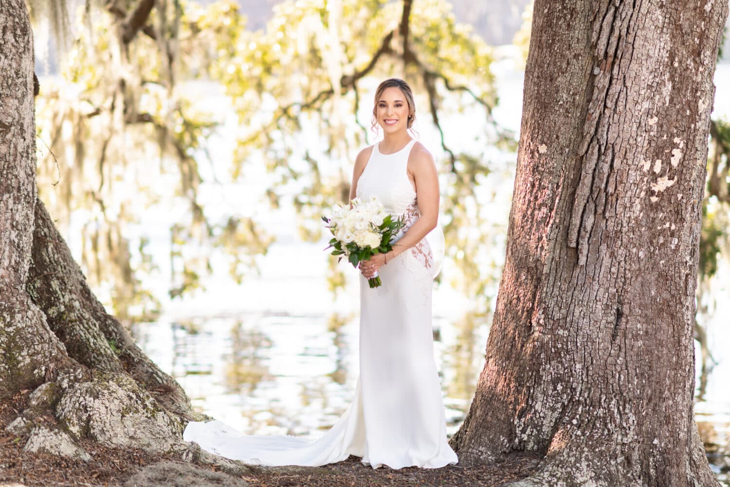 Bride standing under the large oak tree by the river - Kimbels at Wachesaw Plantation