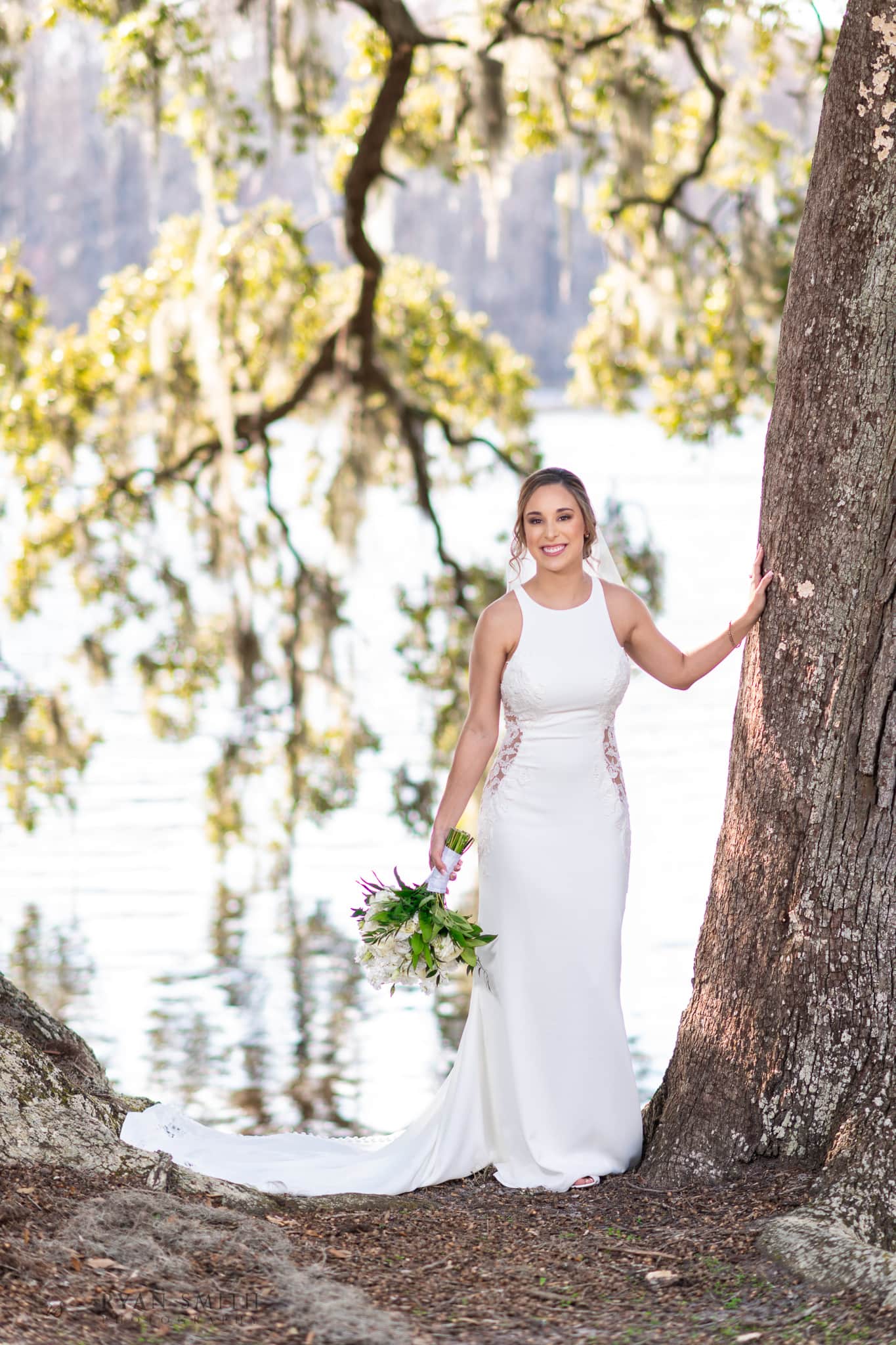 Bride standing under the large oak tree by the river - Kimbels at Wachesaw Plantation