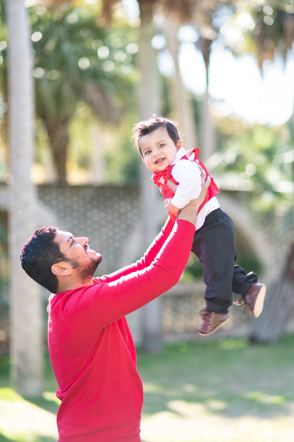 Dad holding baby boy in the air in front of the palm trees - Atalaya Castle