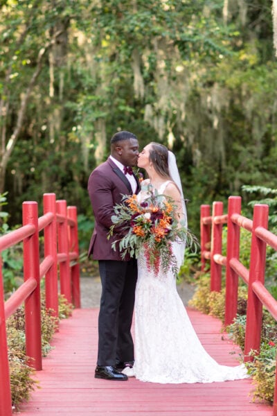 Wedding photography of a bride and groom kissing on a bridge