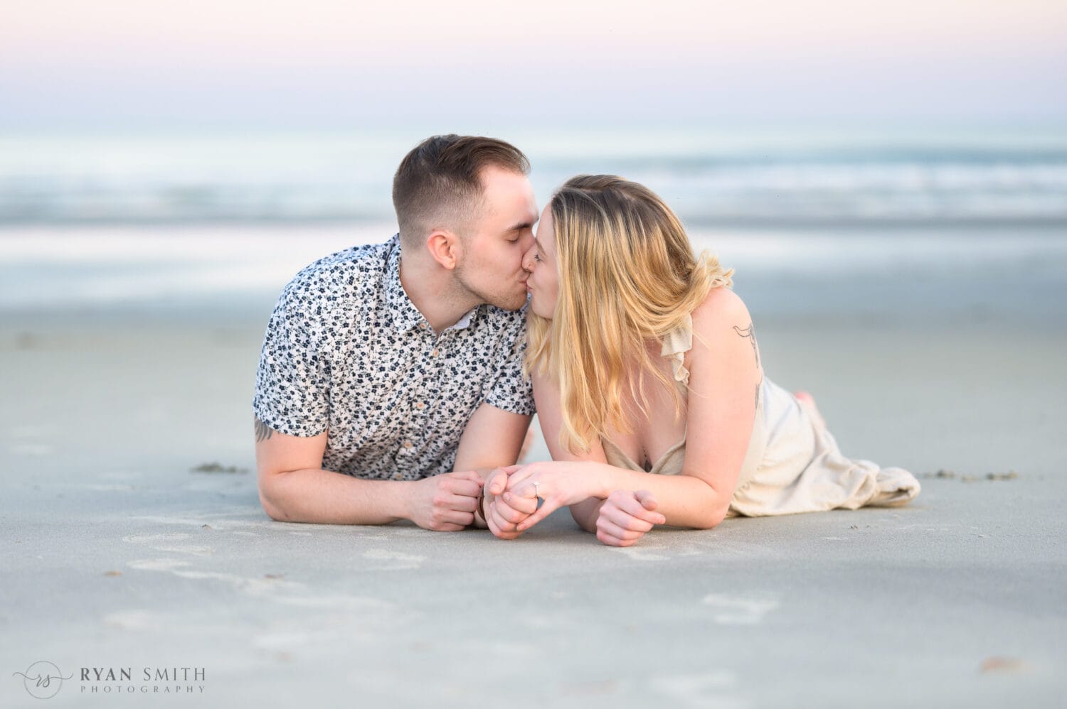 Just engaged couple laying in the sand together - Inlet Point Plantation - Little River