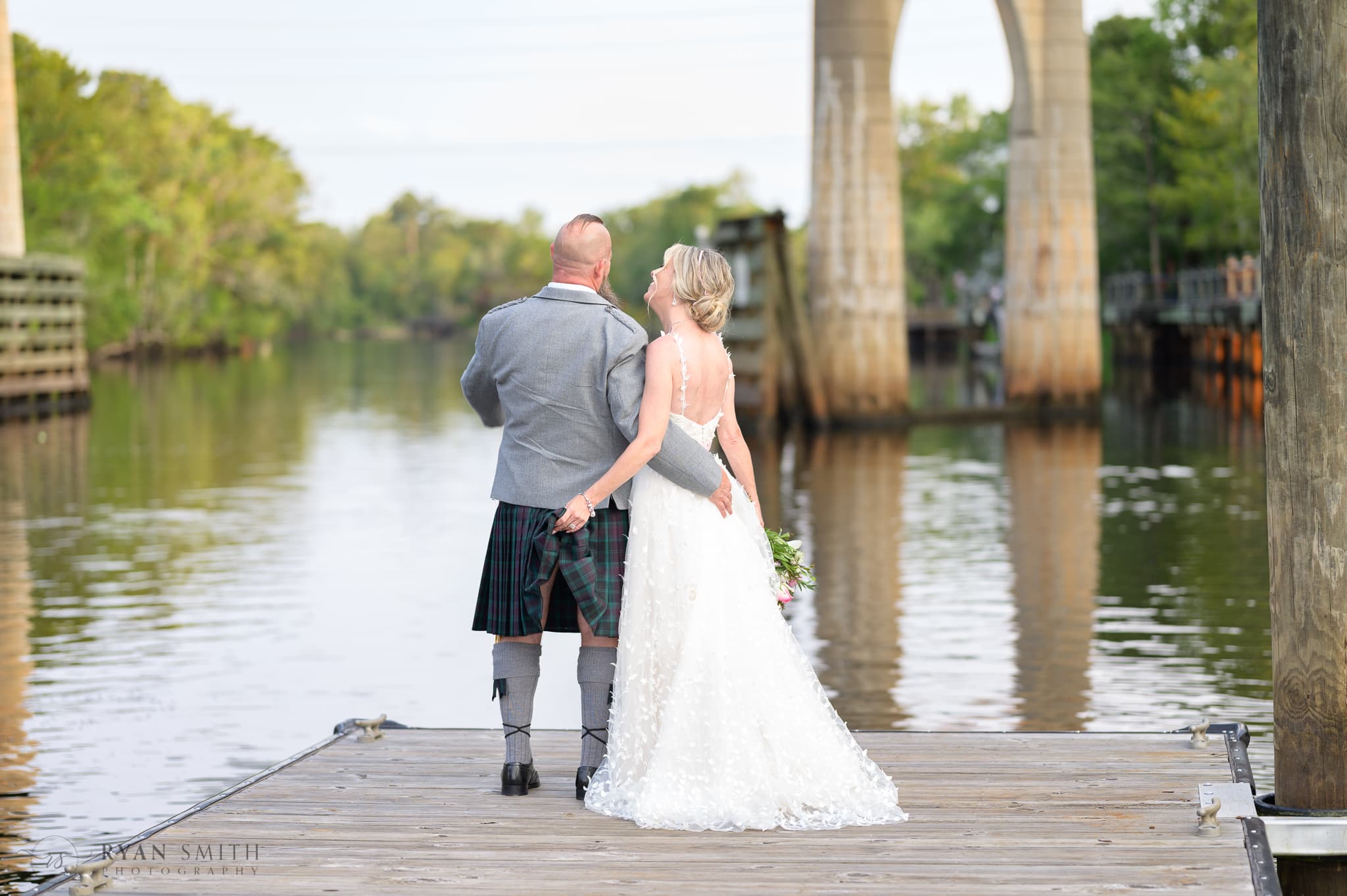 Bride pulling up the grooms kilt like the cake topper - Conway Riverwalk