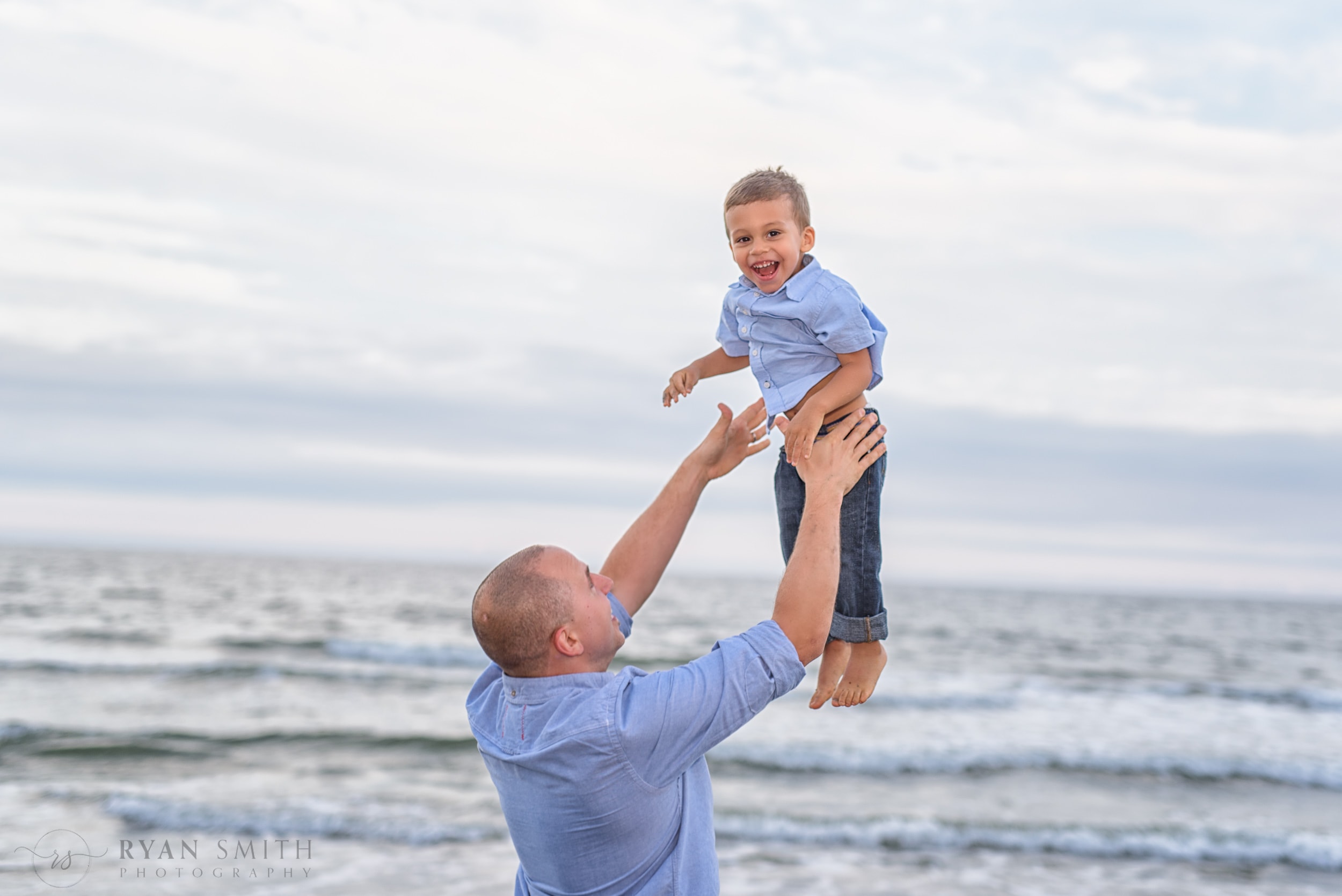 Dad throwing son into the air in front of the ocean - Myrtle Beach