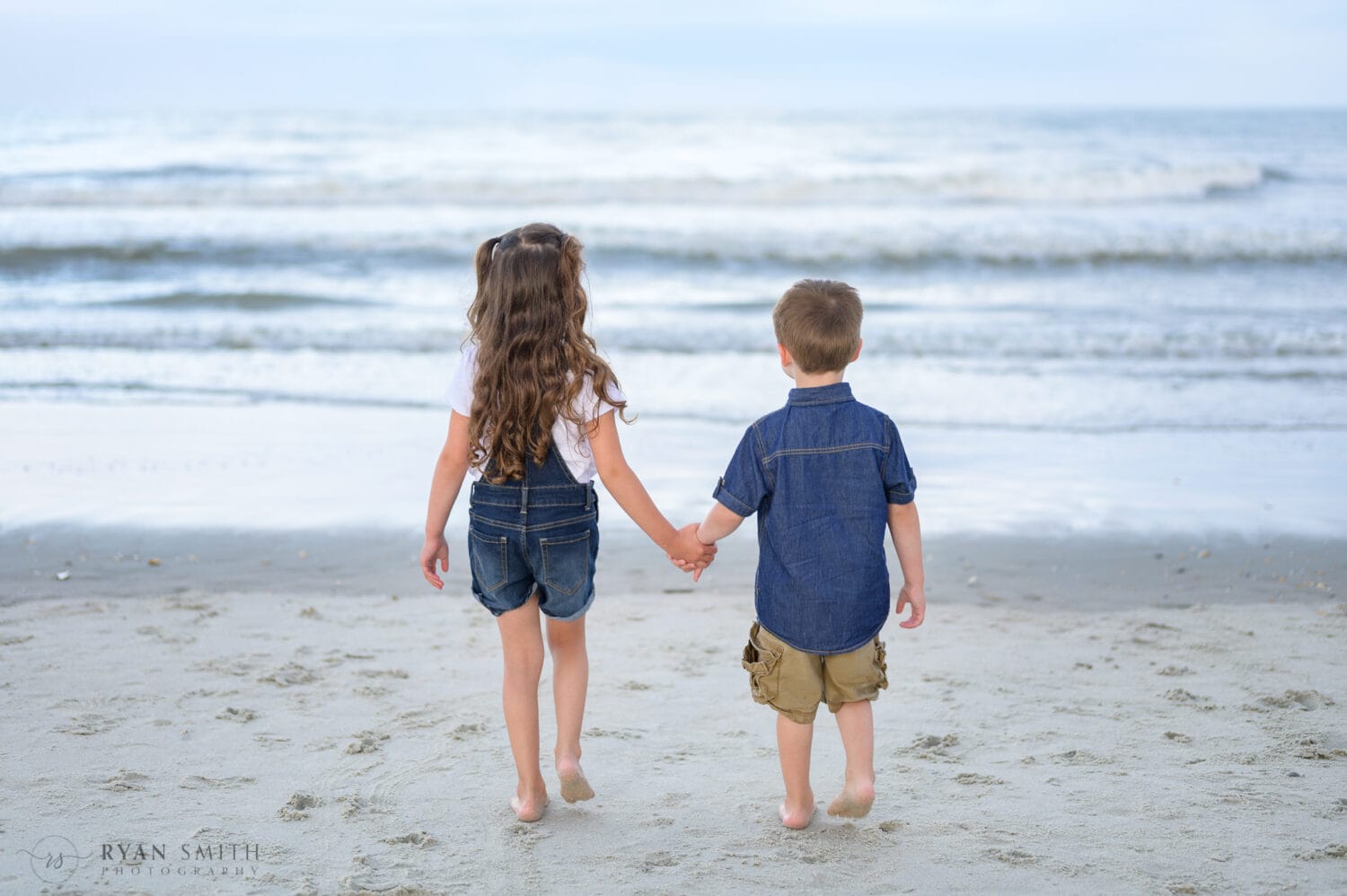 Kids holding hands walking down the beach - Huntington Beach State Park