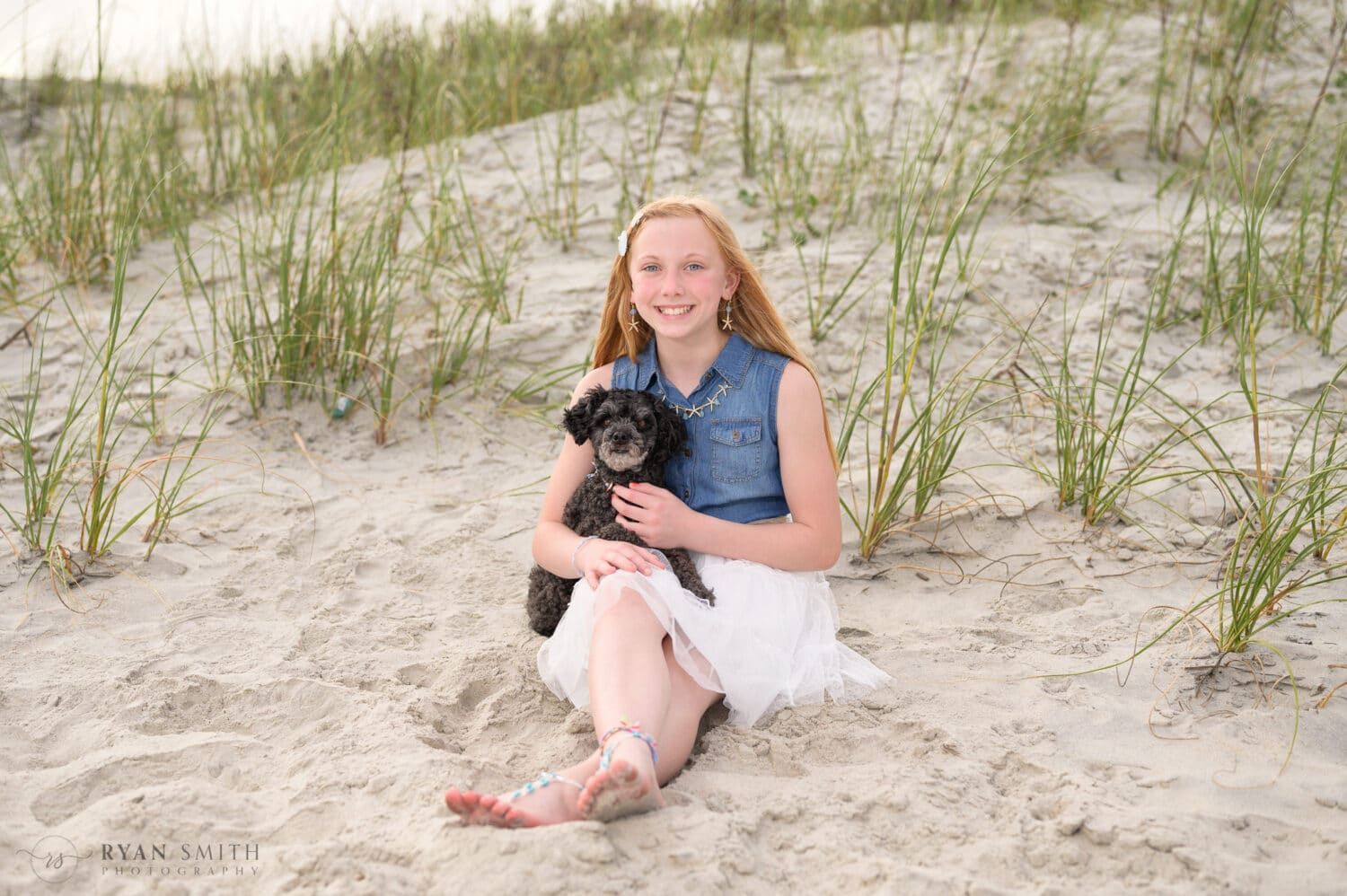 Little girl sitting by the dunes holding her poodle - Huntington Beach State Park