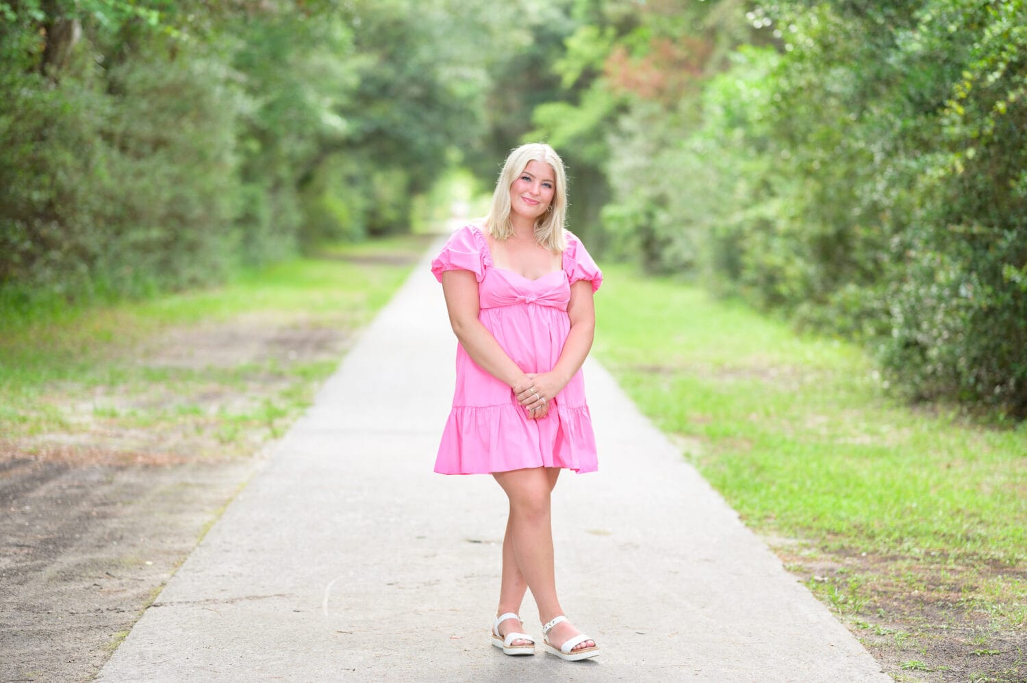 Senior portrat of girl in pink dress standing on the Atalaya Pathway - Huntington Beach State Park