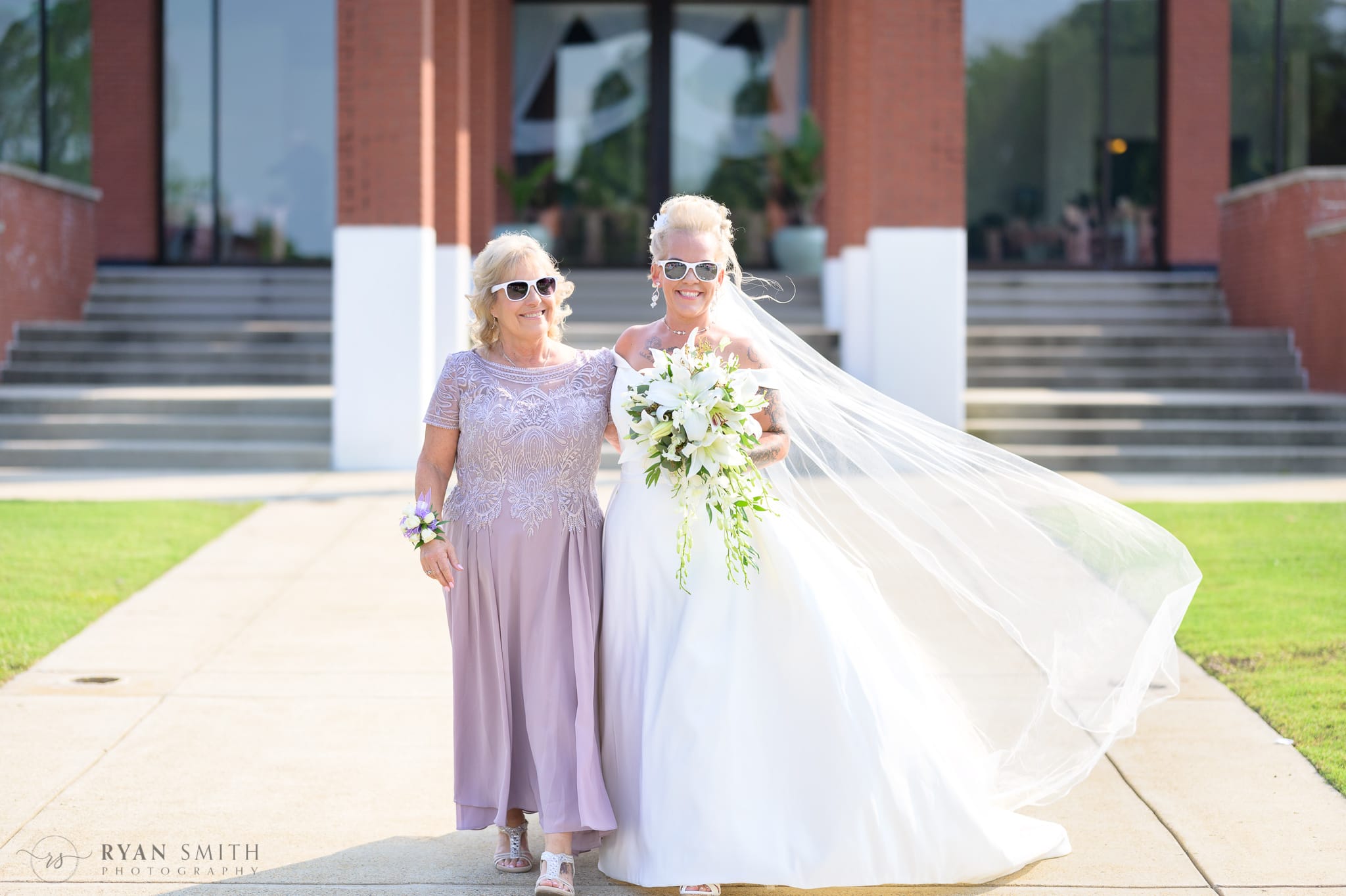Mother walking bride down the aisle with white sunglasses  - Wild Wing Plantation
