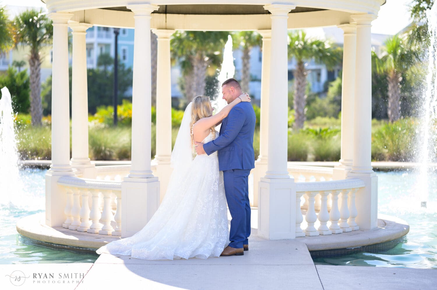 Bride and groom embracing under the gazebo  - North Beach Resort & Villas