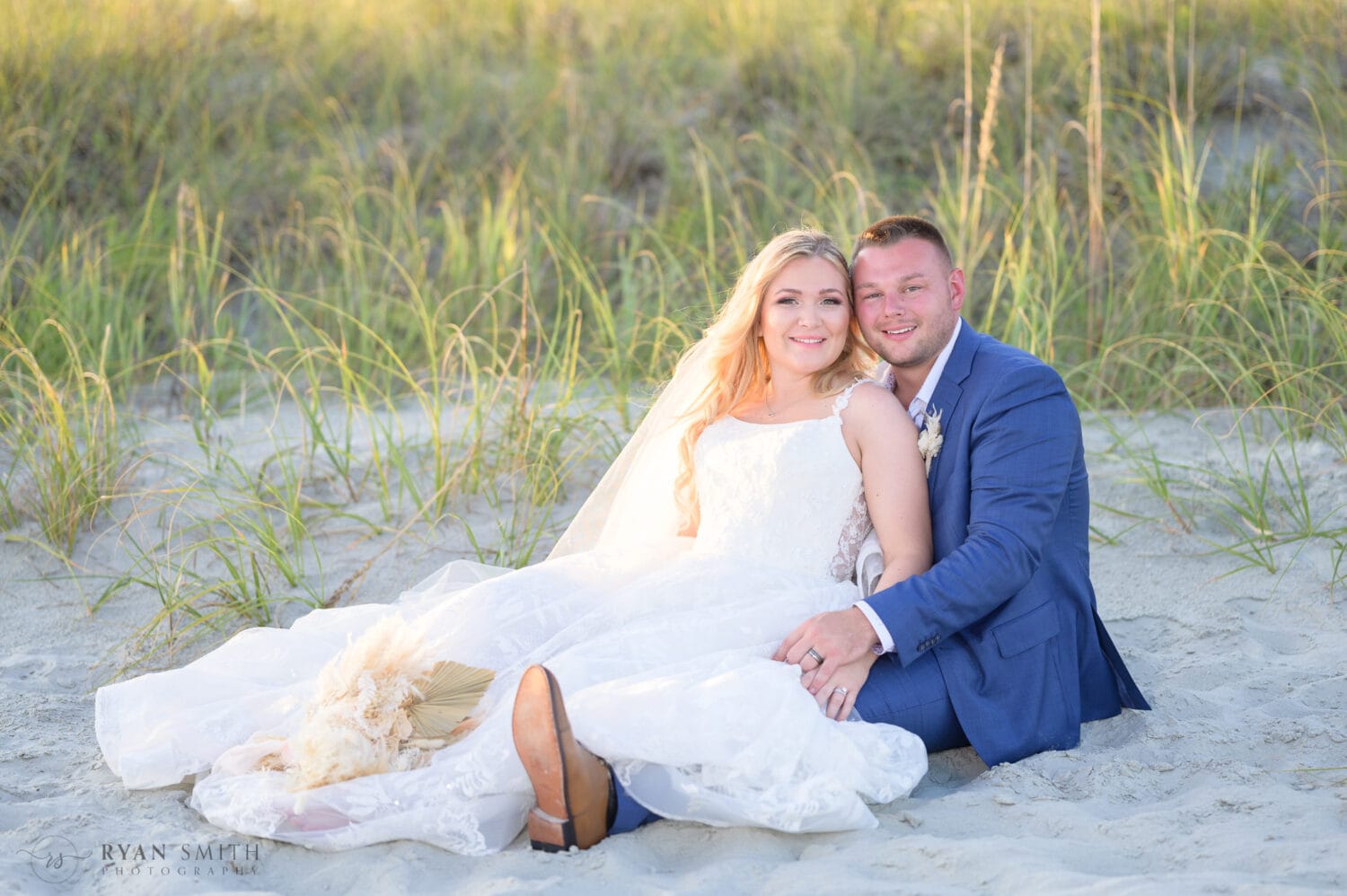 Bride and groom laying together by the dunes - North Beach Resort & Villas