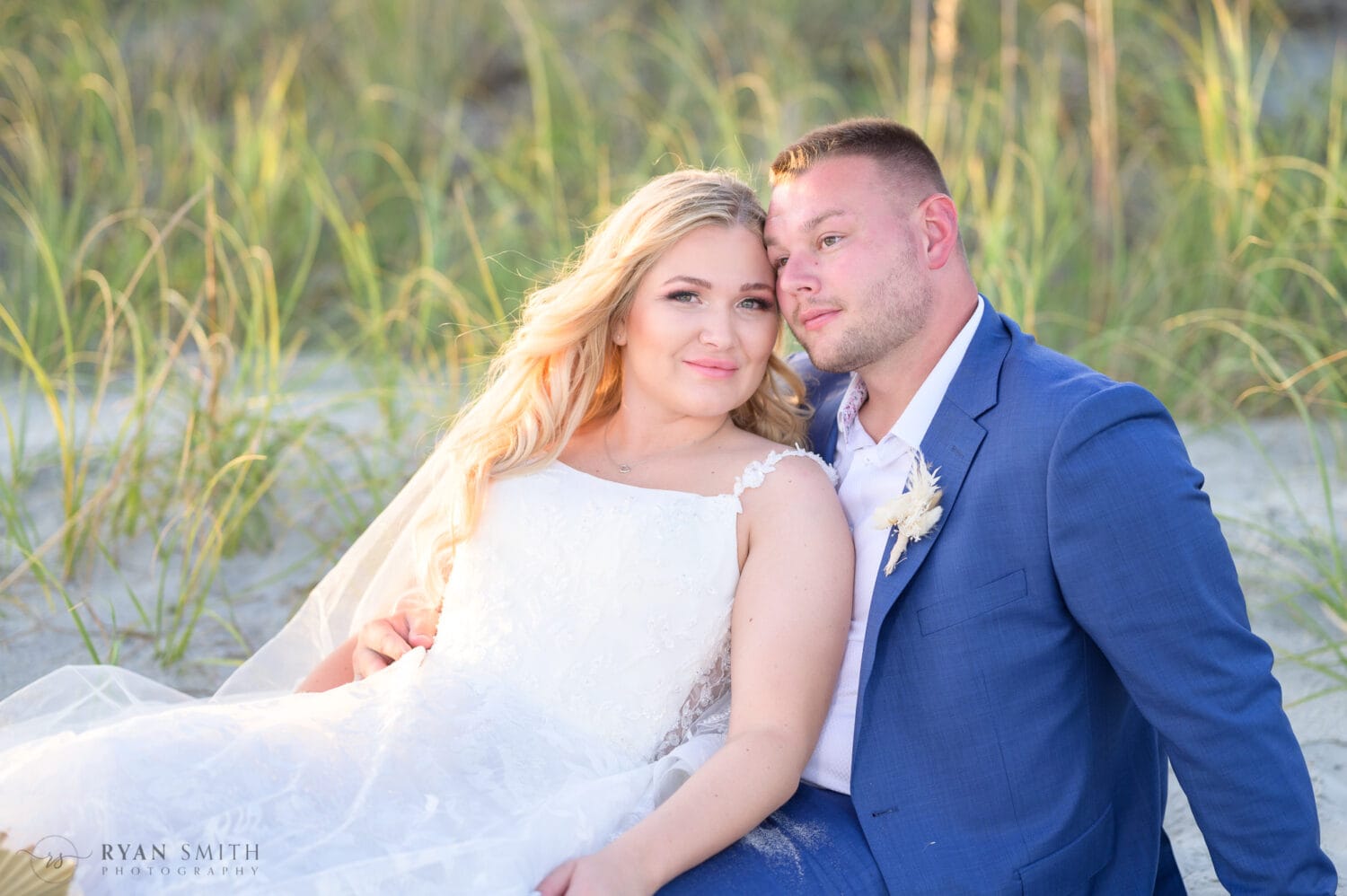 Bride and groom laying together by the dunes - North Beach Resort & Villas