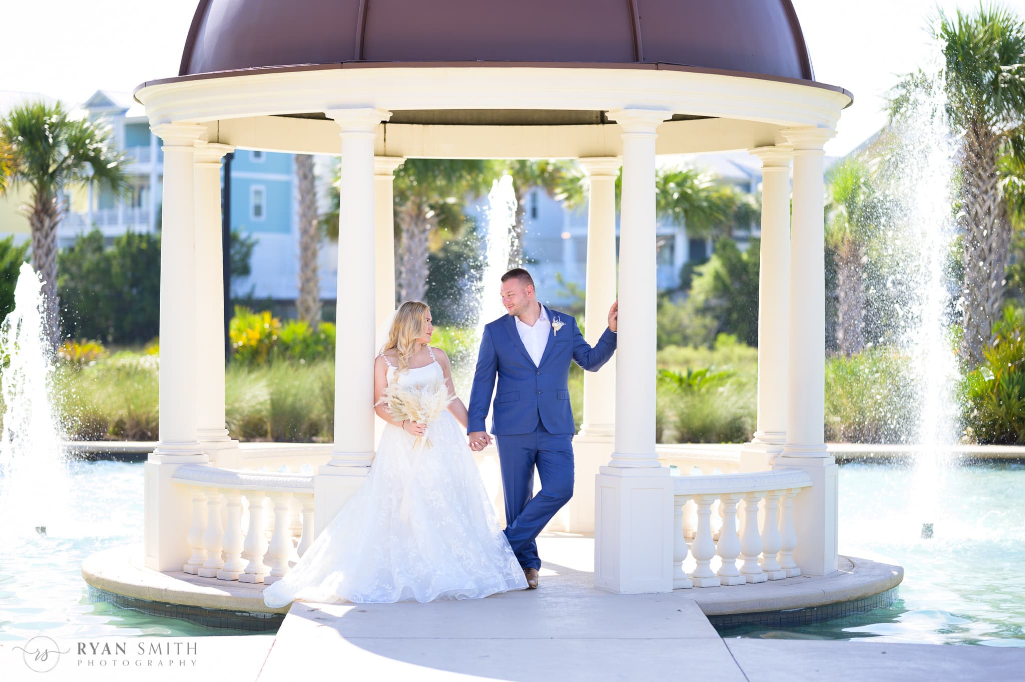 Bride and groom leaning against the columns of the gazebo  - North Beach Resort & Villas