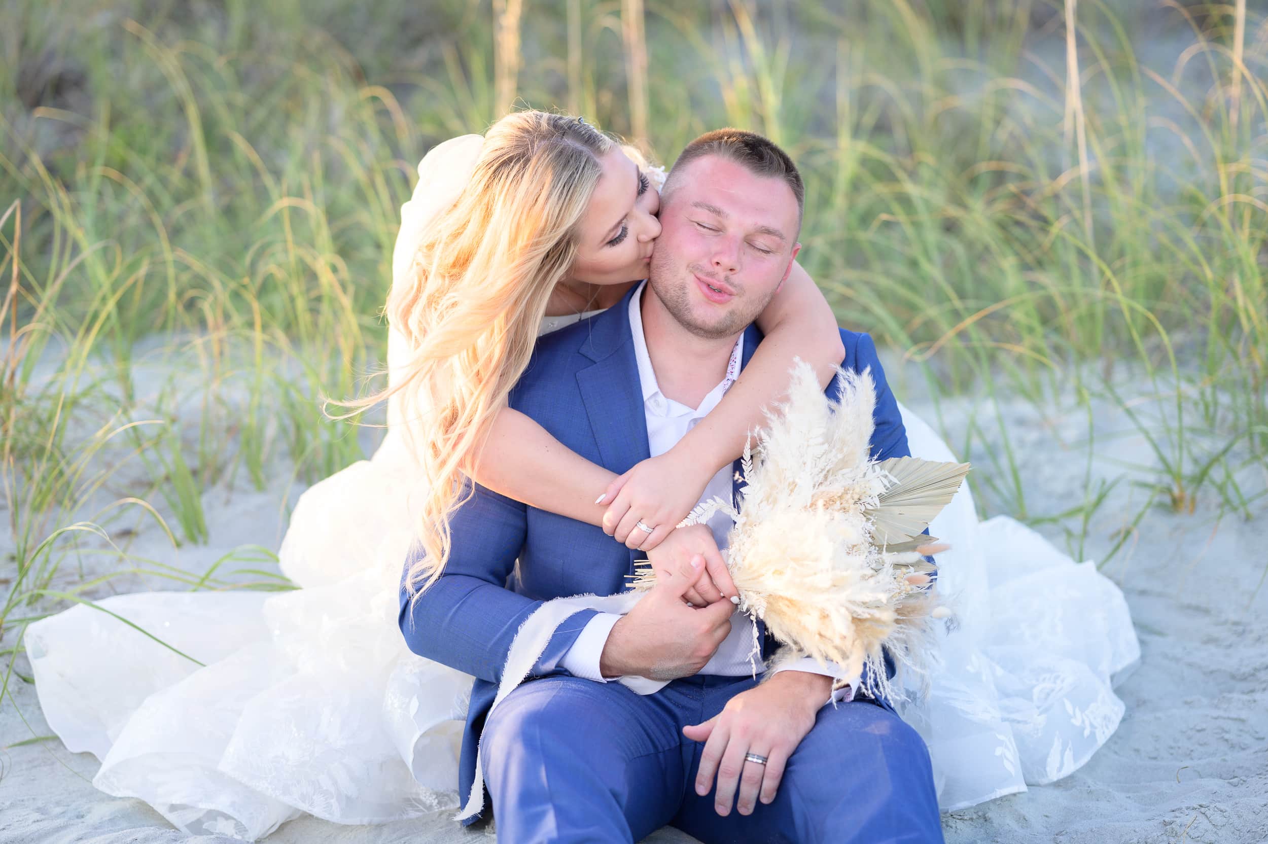 Bride hugging groom from behind and kissing on the cheek - North Beach Resort & Villas
