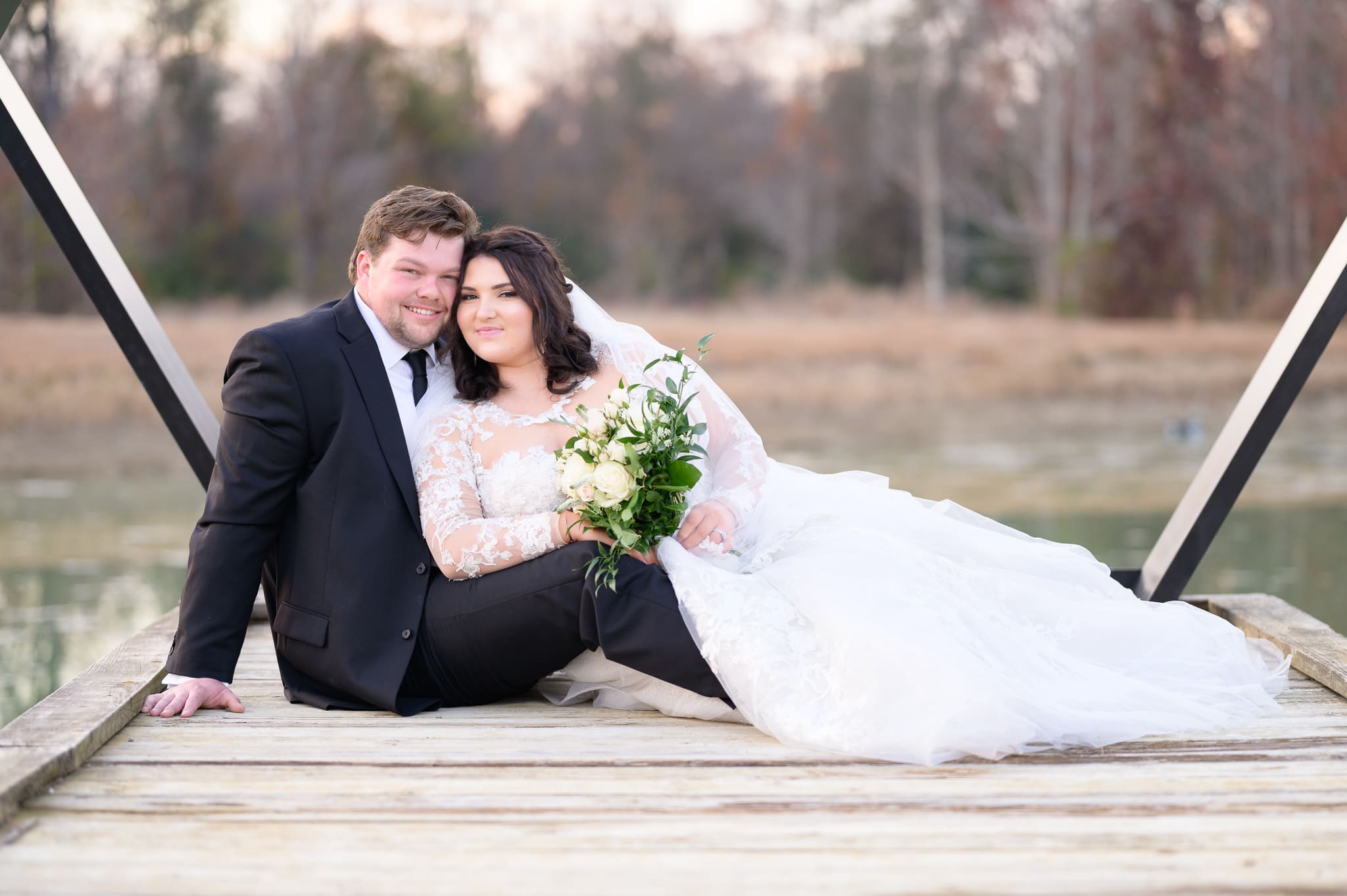 Bride and groom laying together on the dock - The Venue at White Oaks Farm