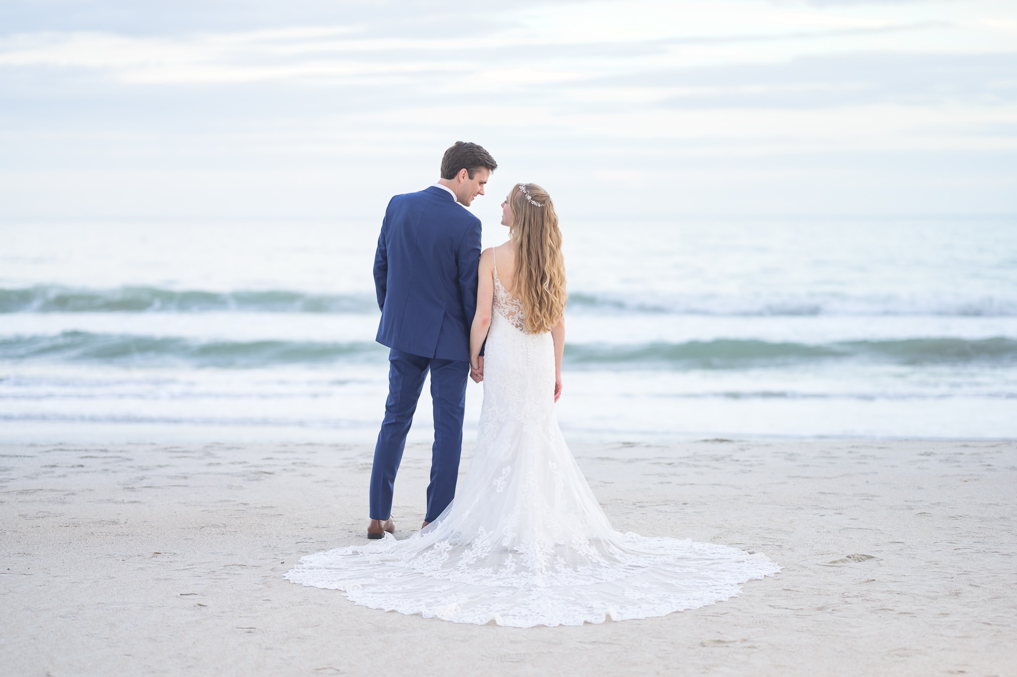 Bride and groom standing in front of the ocean -