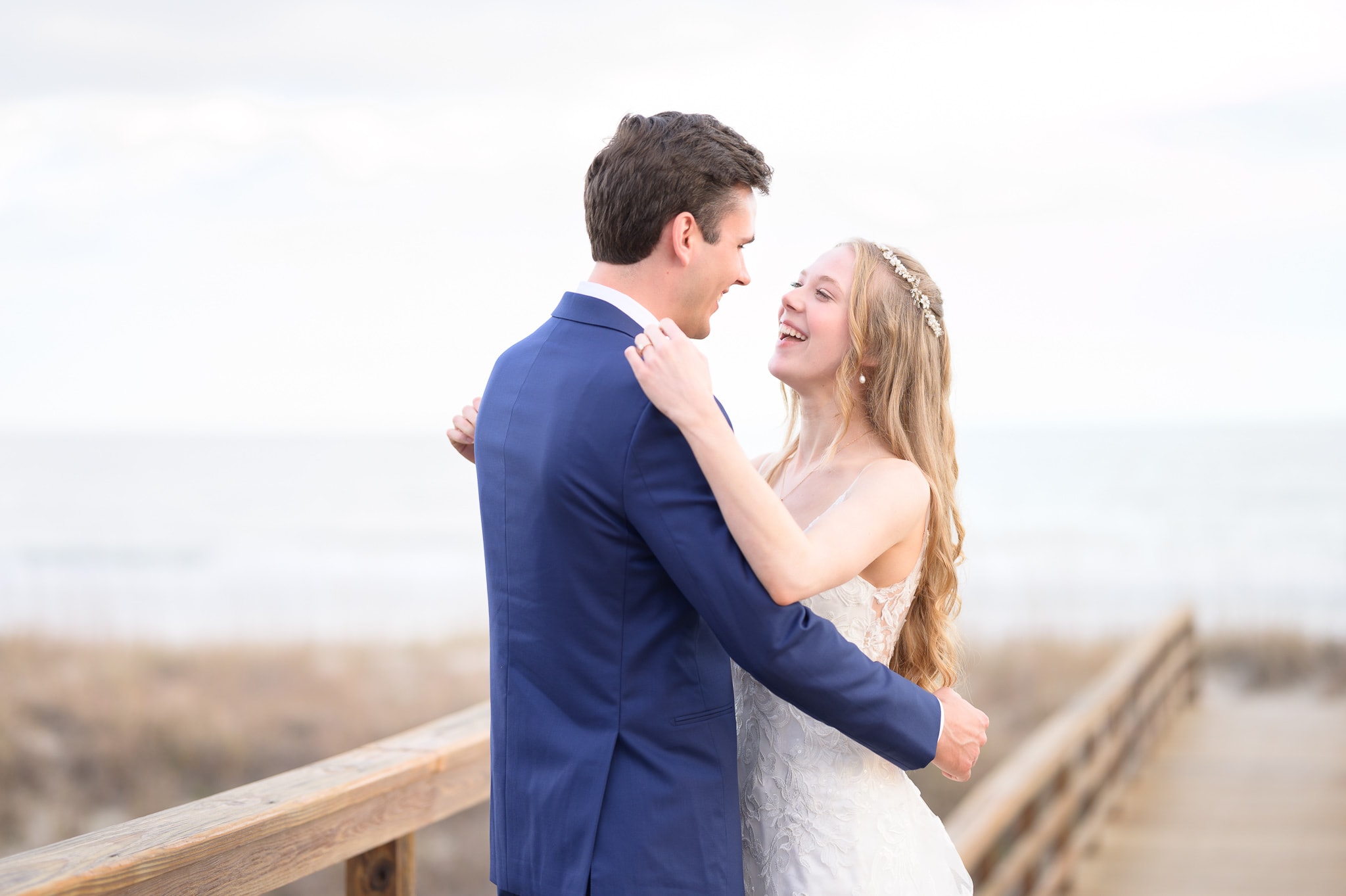 Happy first look with bride and groom on the beach boardwalk -