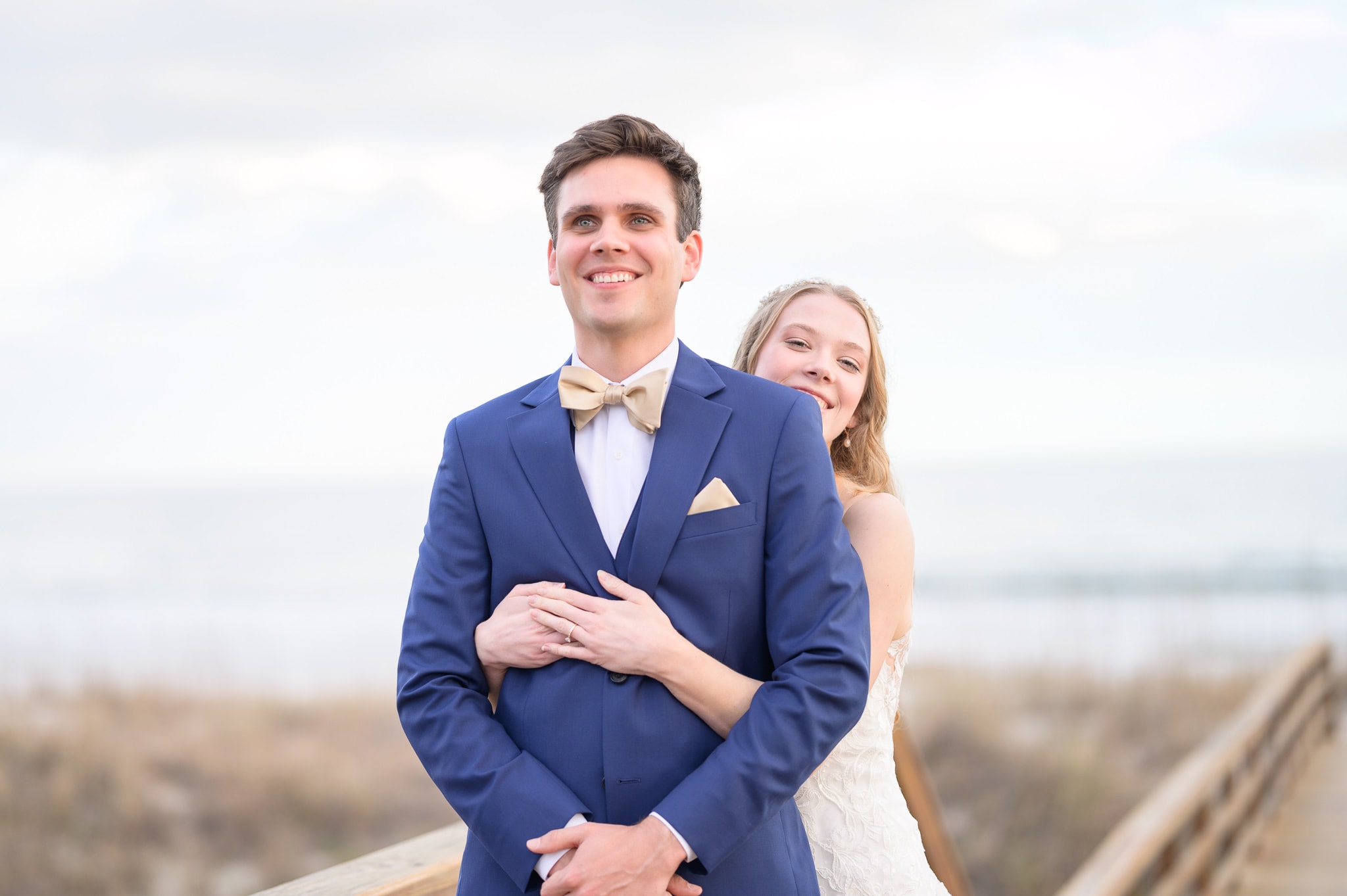 Happy first look with bride and groom on the beach boardwalk -