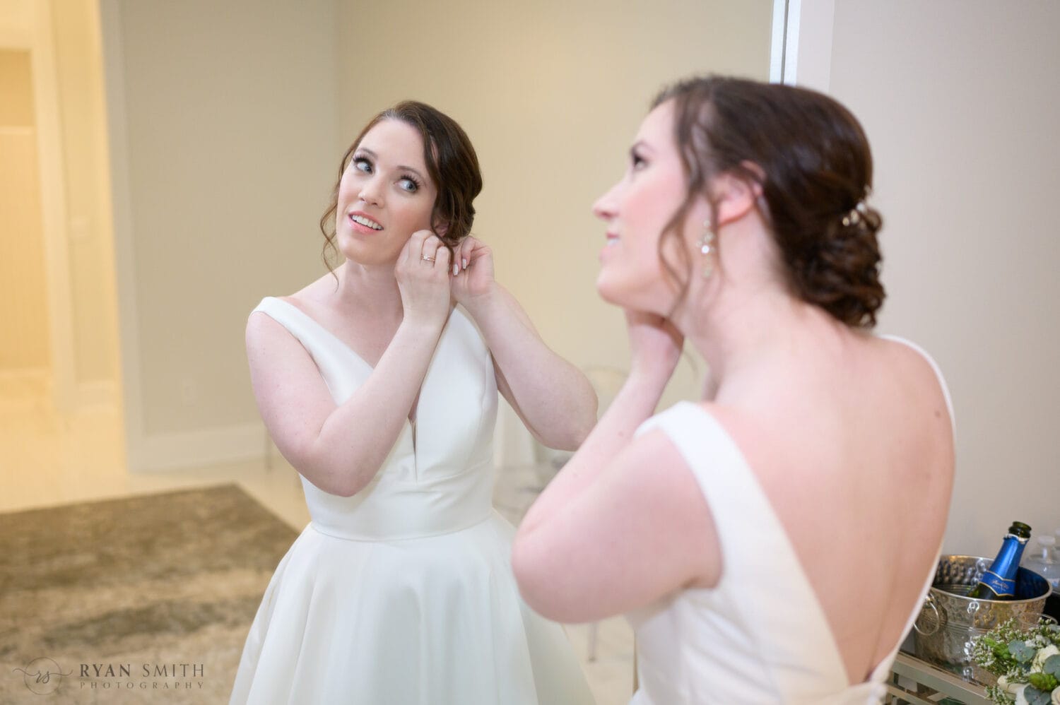 Bride putting earrings on in mirror - 21 Main Events at North Beach