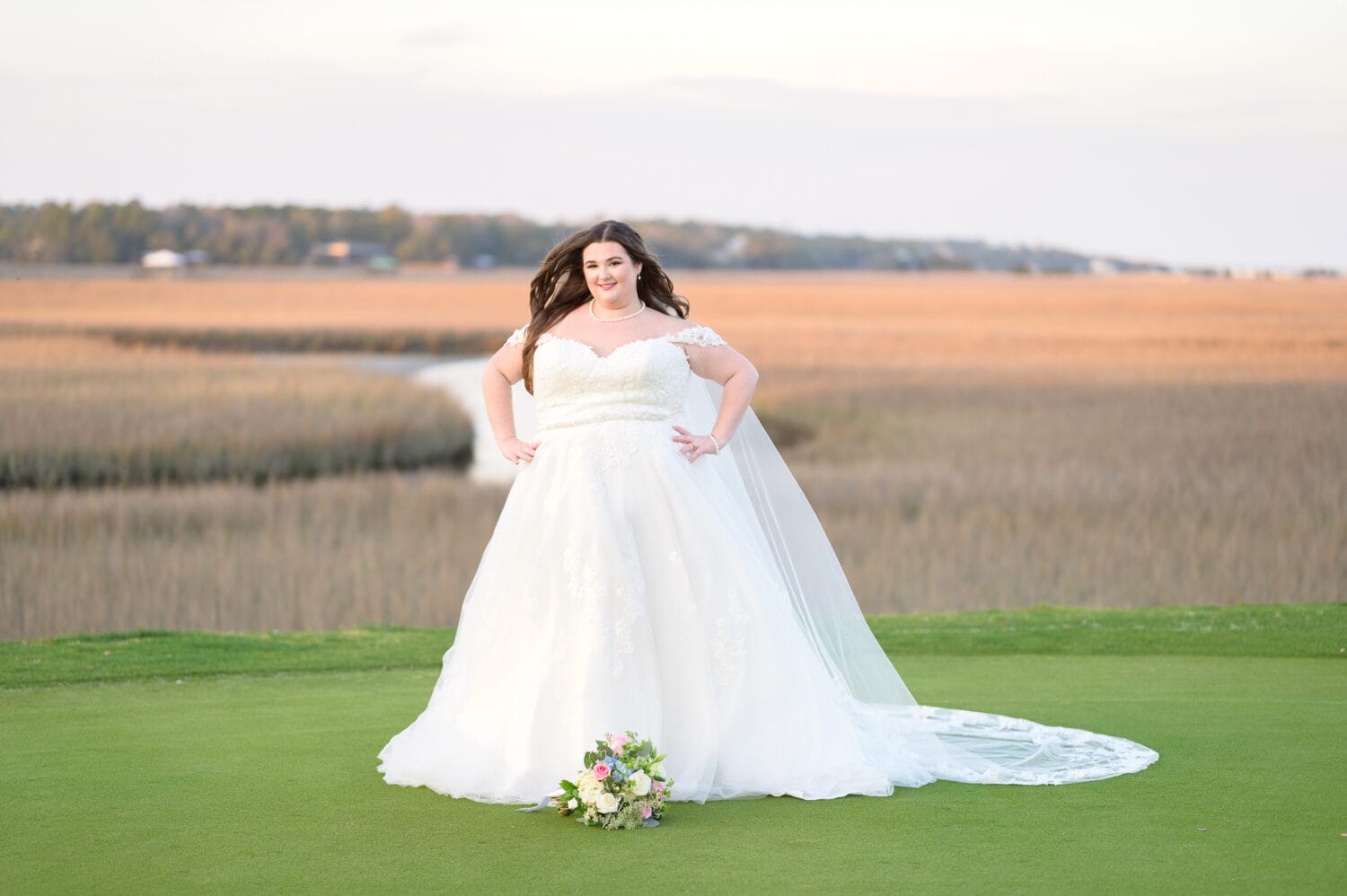 Bride posing with hands on her hips in front of the marsh - Pawleys Plantation Golf & Country Club