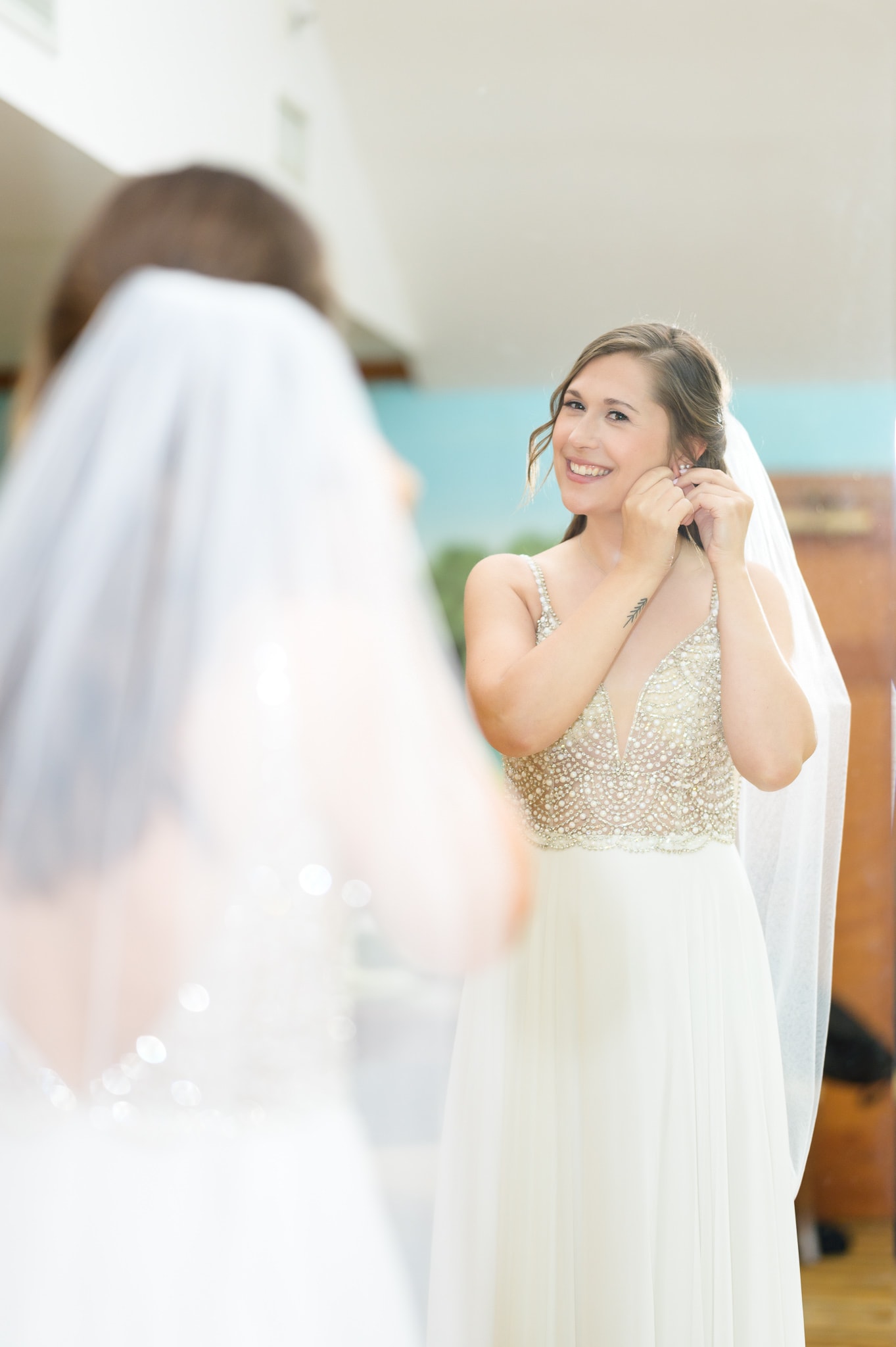 Bride putting earrings on in the mirror - Caledonia Golf & Fish Club