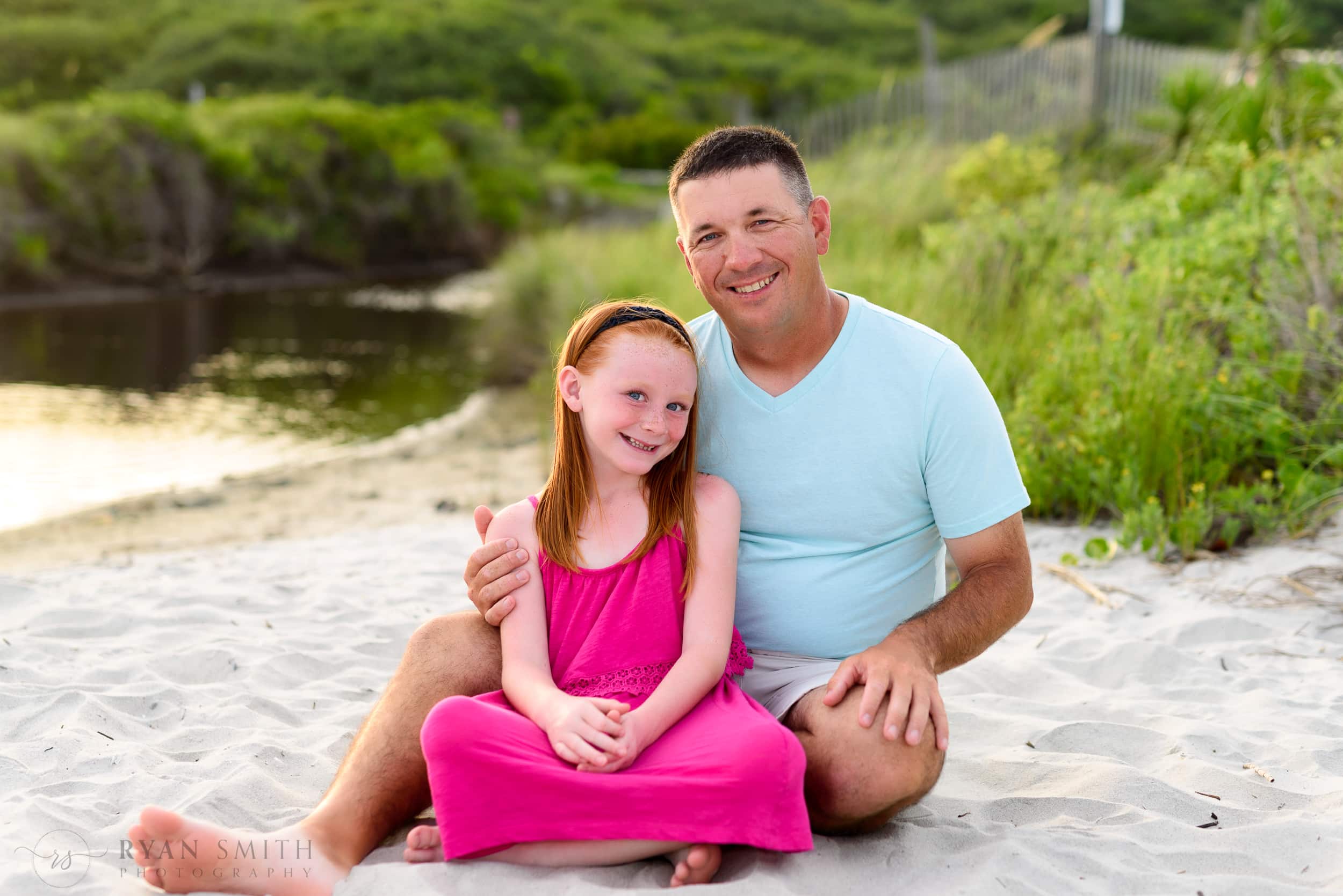 Dad and daughter sitting by the dunes - Myrtle Beach State Park