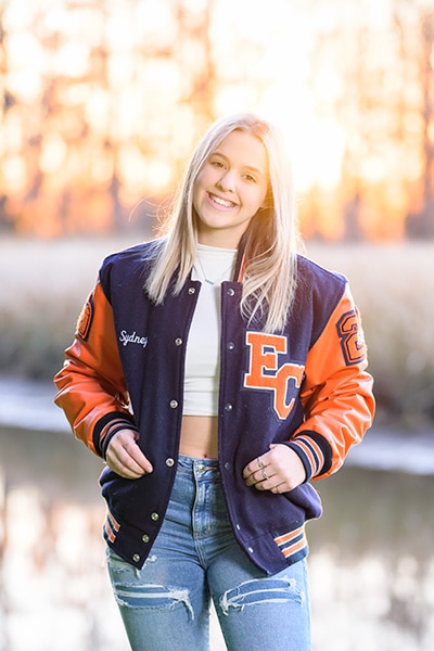 Senior portrait of a girl in her school jacket at sunset