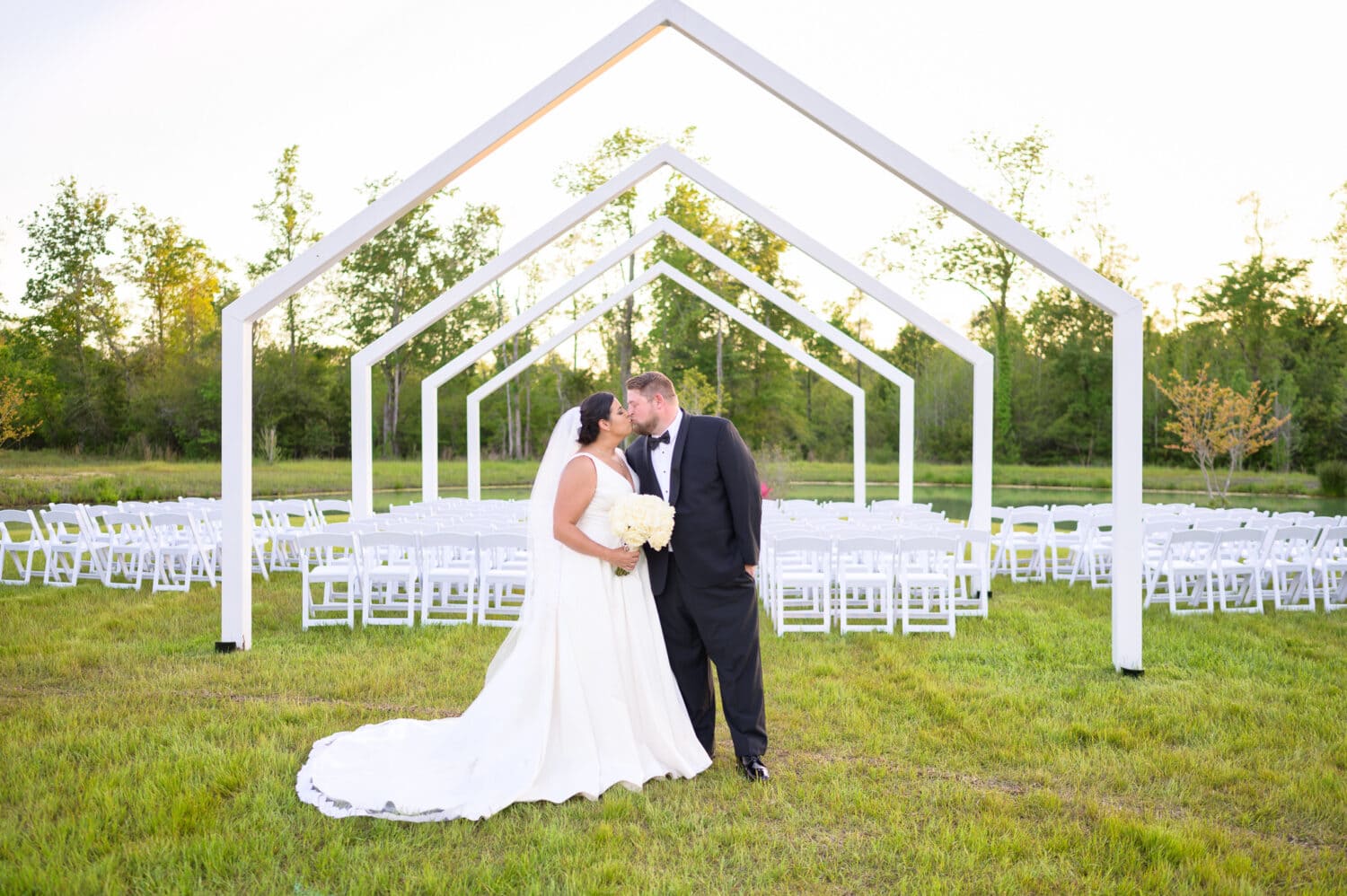 Wide angle kiss in front of the ceremony area at sunset - The Venue at White Oaks Farm