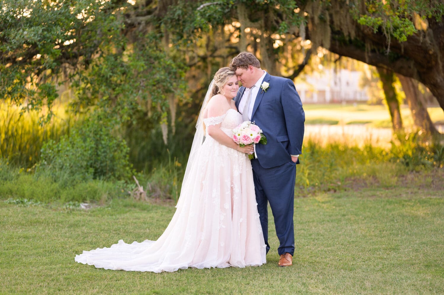 Bride and groom embracing under the oaks on the golf course - Pawleys Plantation