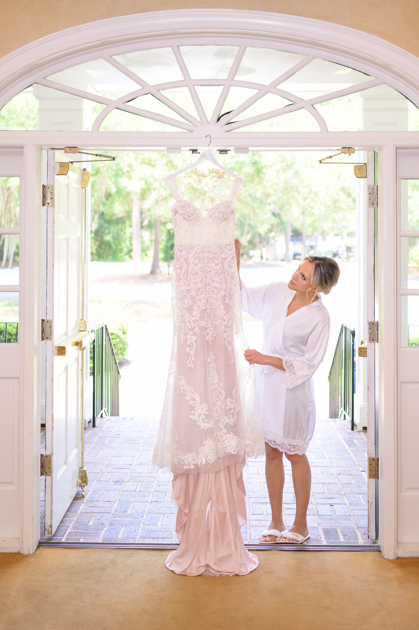 Bride looking at dress hanging in the doorway - Pawleys Plantation Golf & Country Club
