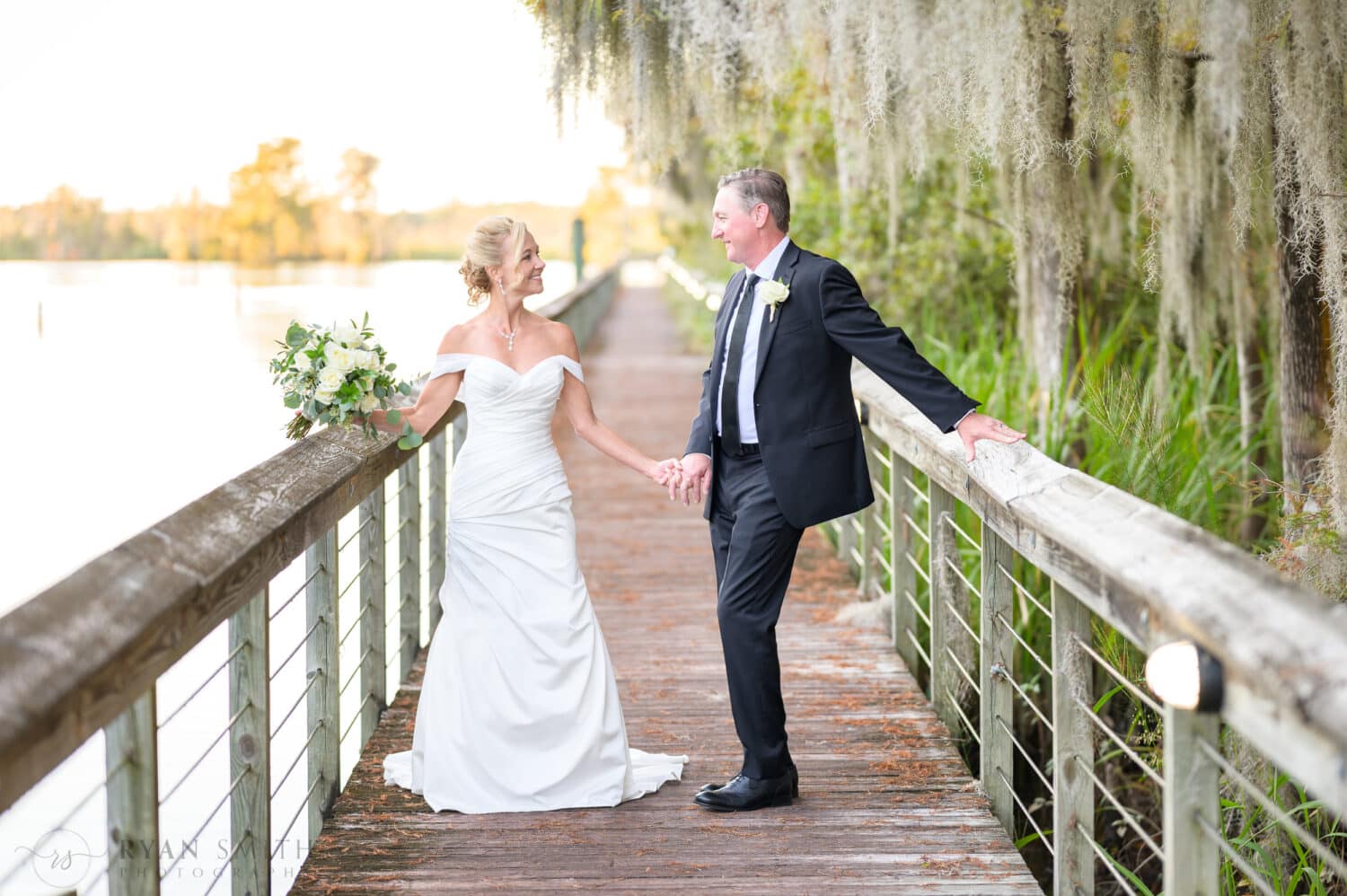 Bride and groom holding hands on the boardwalk on the Waccamaw River - Safe Harbor Reserve Harbor Yacht Club