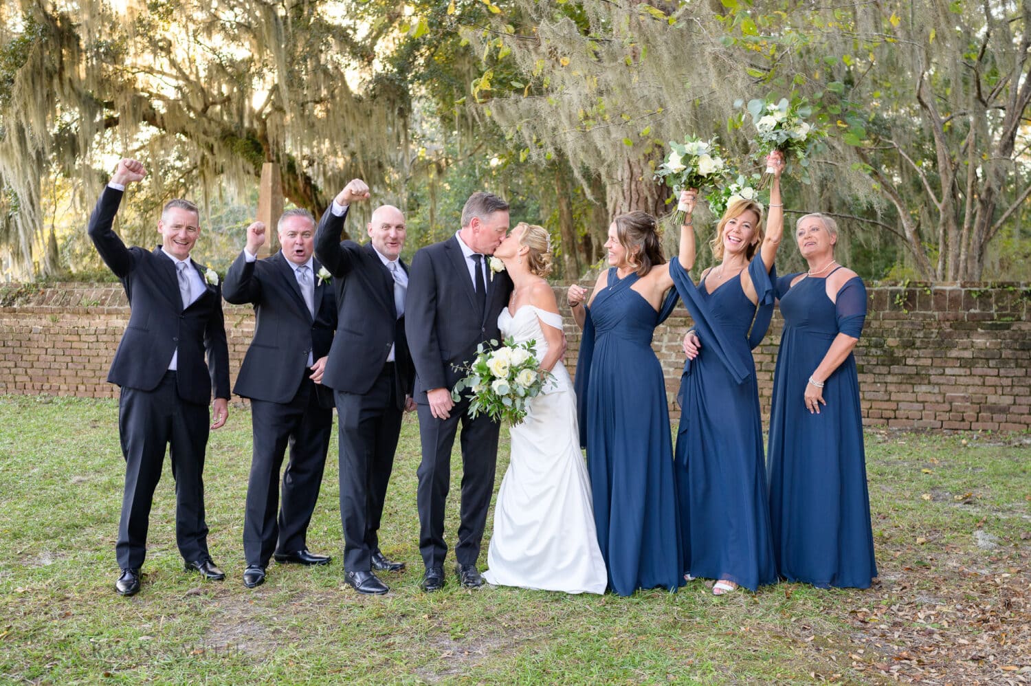 Bride and groom kissing with bridal party cheering - Safe Harbor Reserve Harbor Yacht Club