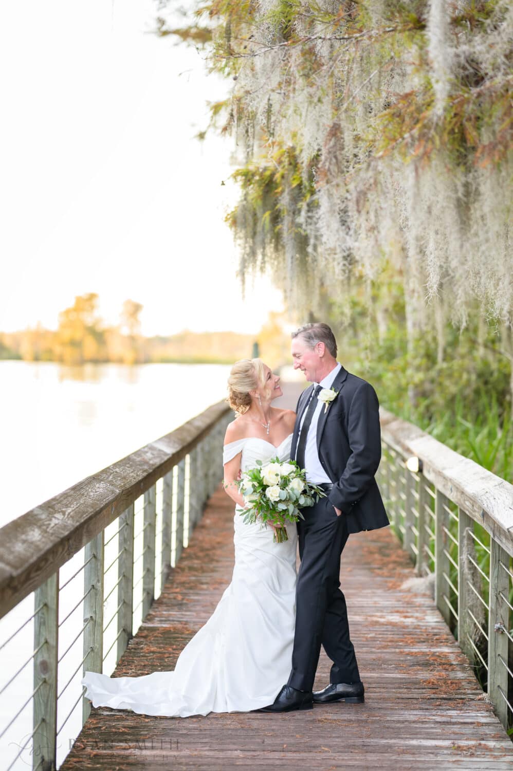 Bride and groom looking into each others eyes on the marsh boardwalk - Safe Harbor Reserve Harbor Yacht Club