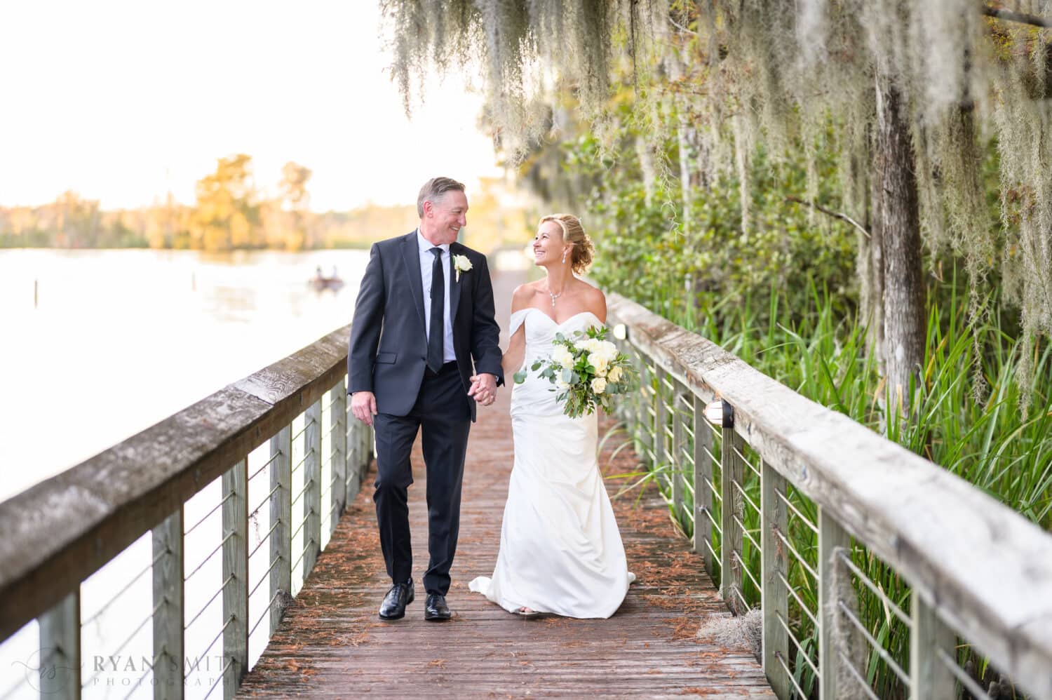 Holding hands walk down the boardwalk on the Waccamaw River - Safe Harbor Reserve Harbor Yacht Club