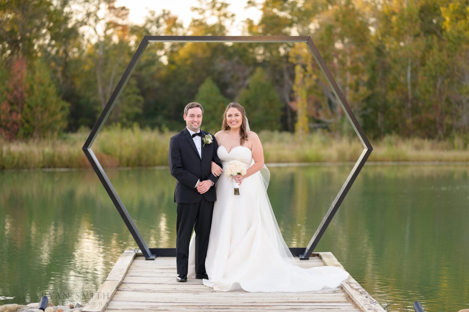 Portrait of bride and groom in front of the hexagon by the lake - The Venue at White Oaks Farm