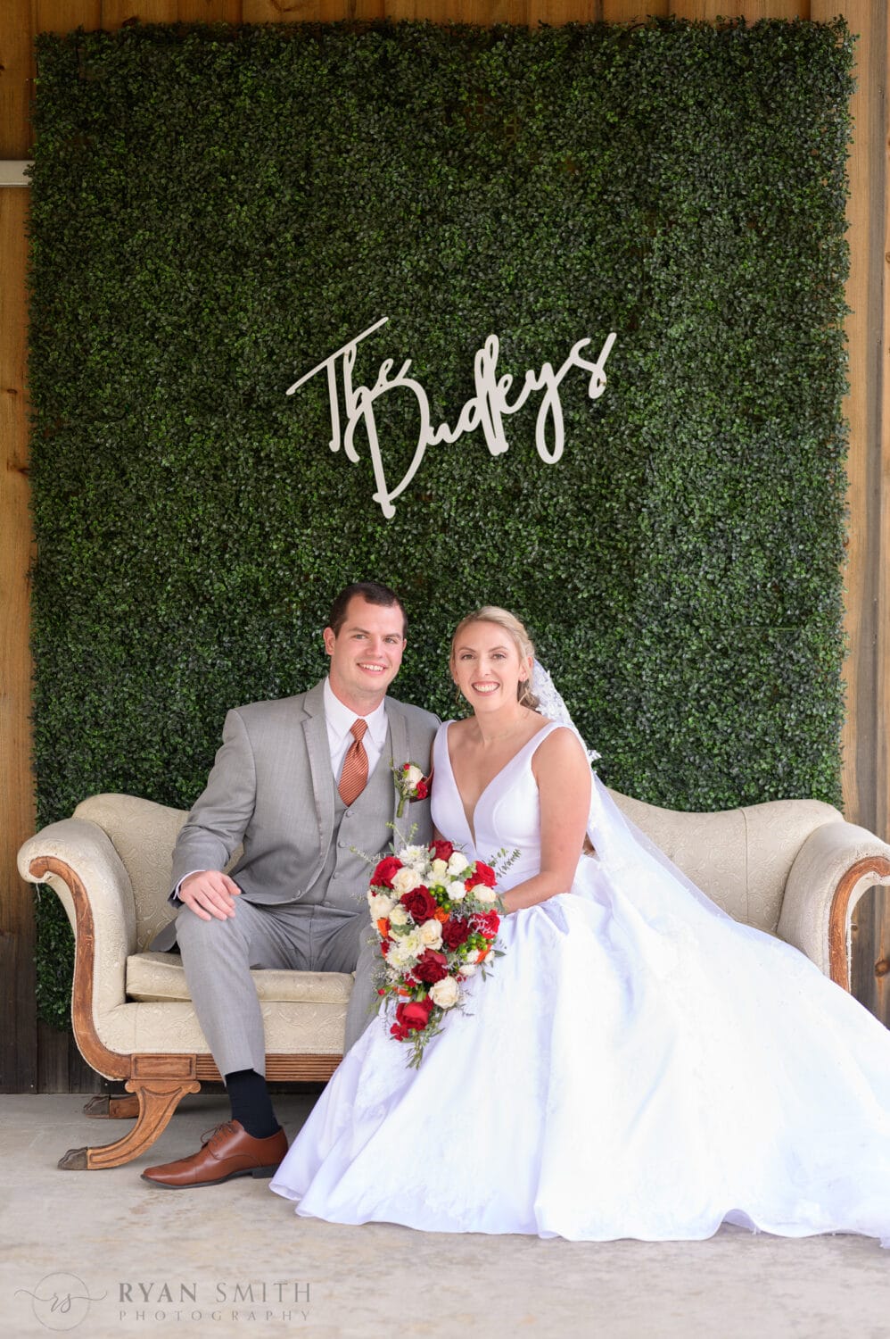Bride and groom on the couch under the ivy wall - The Blessed Barn