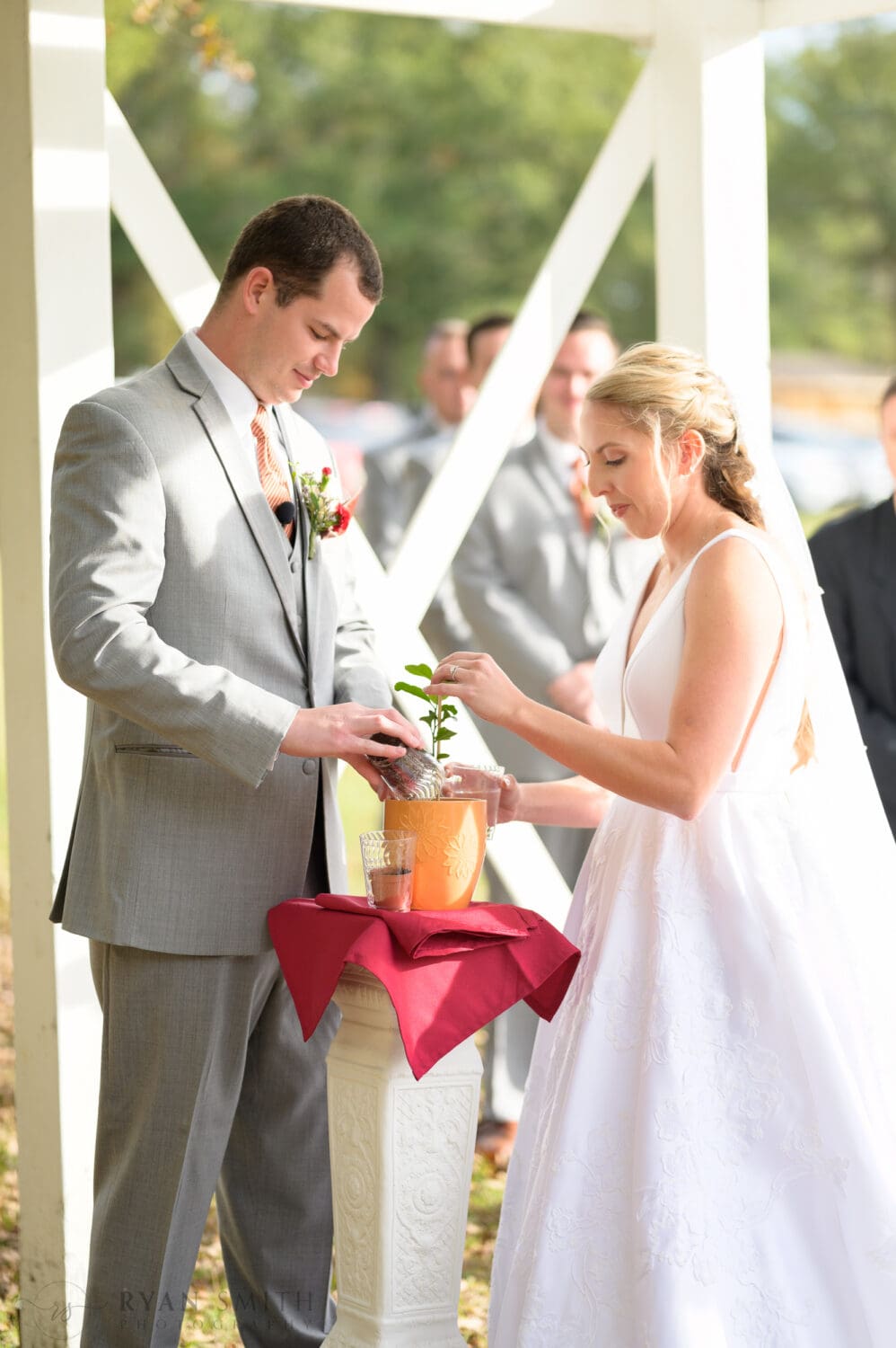 Bride and groom planting a tree together during the ceremony - The Blessed Barn