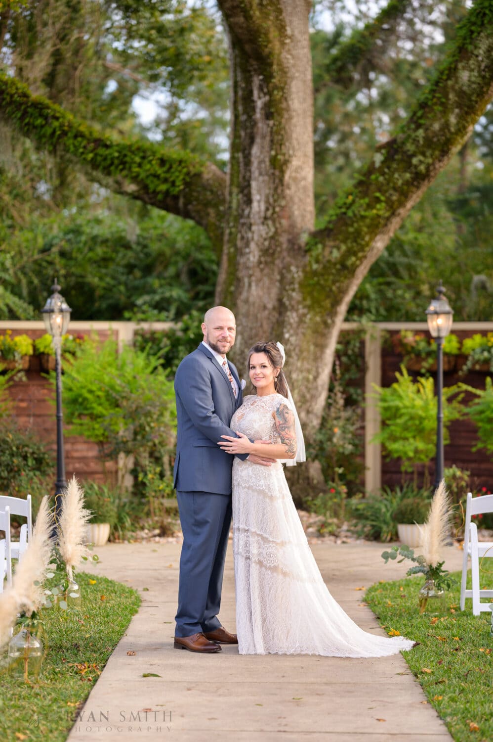 Bride and groom standing in front of the old oak tree - The Cooper House