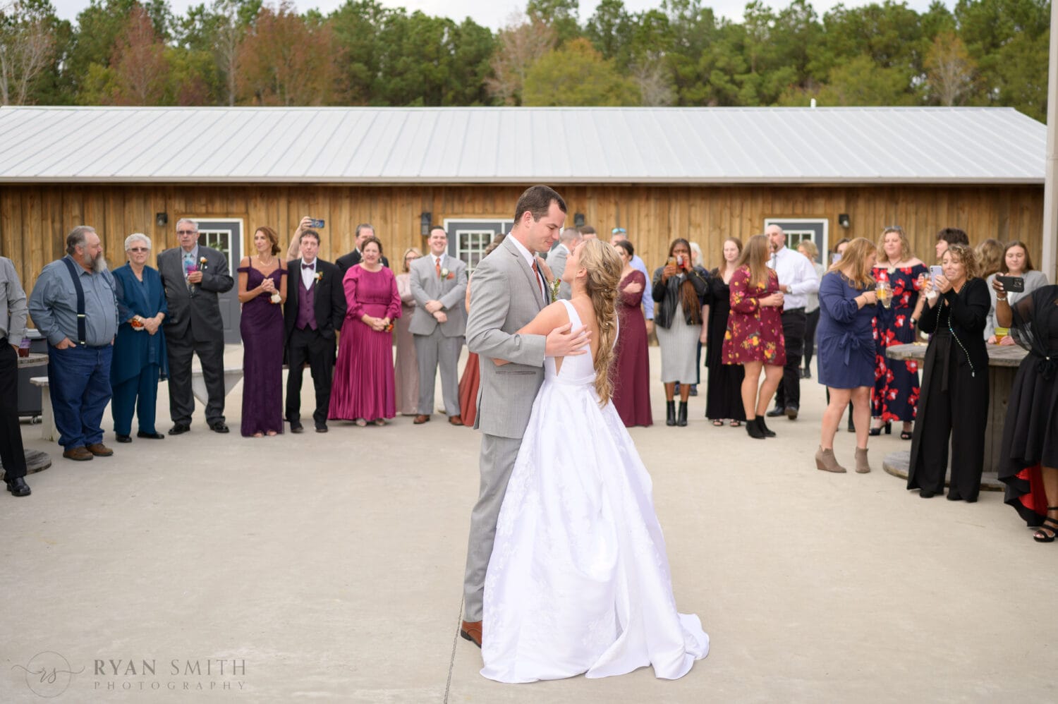 First dance with the bride and groom and family standing in the background - The Blessed Barn