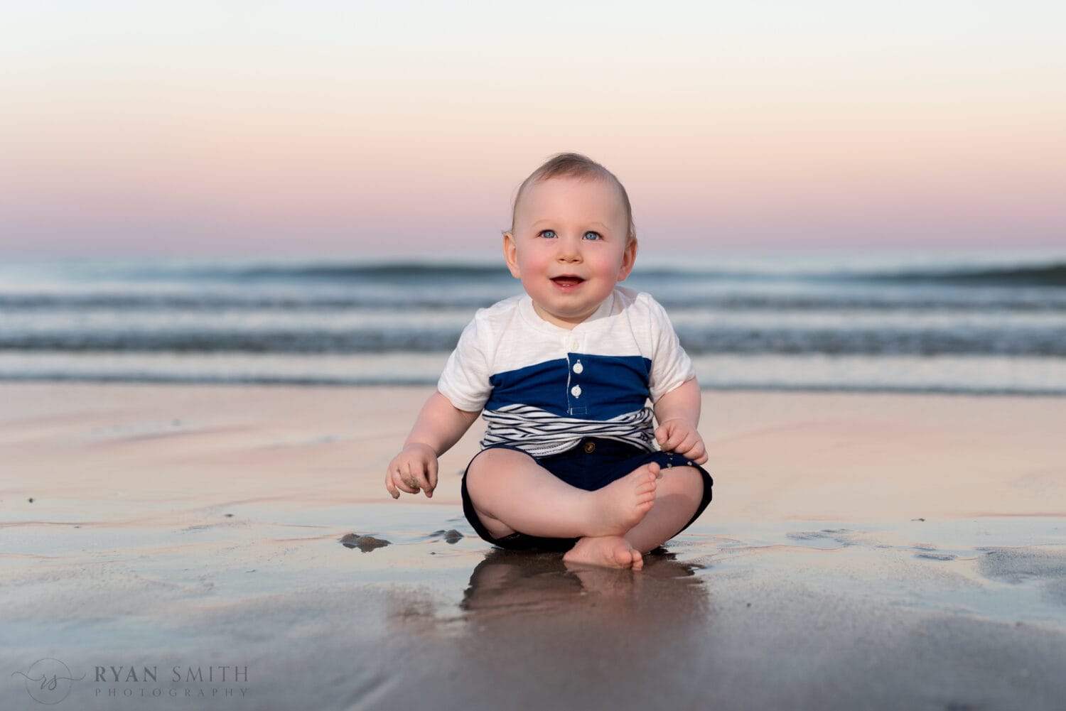 Baby boy sitting by the ocean -