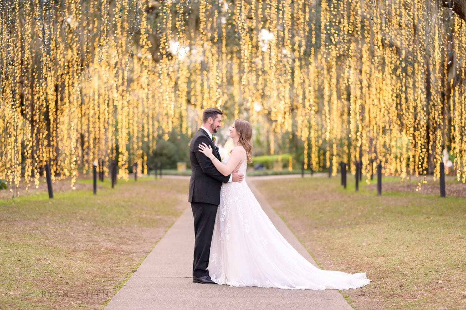 Bride and groom embracing without holding the flowers - Oak Allee - Night of a Thousand Candles - Brookgreen Gardens