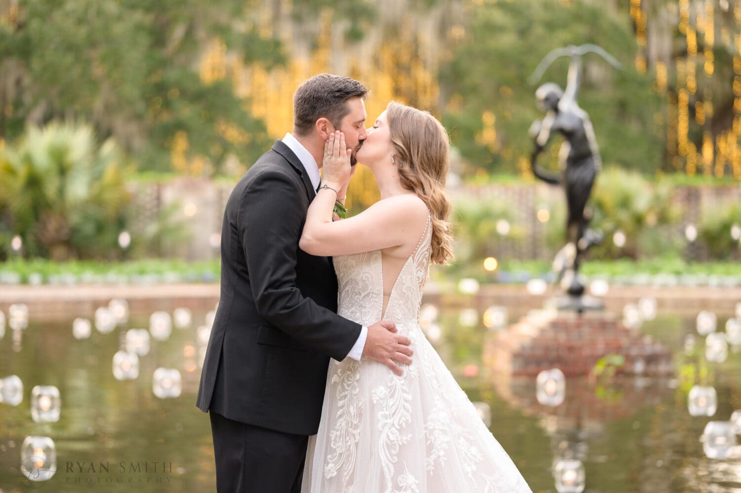 Bride pulling grooms face in for a kiss - Diana of the Chase Fountain - Brookgreen Gardens