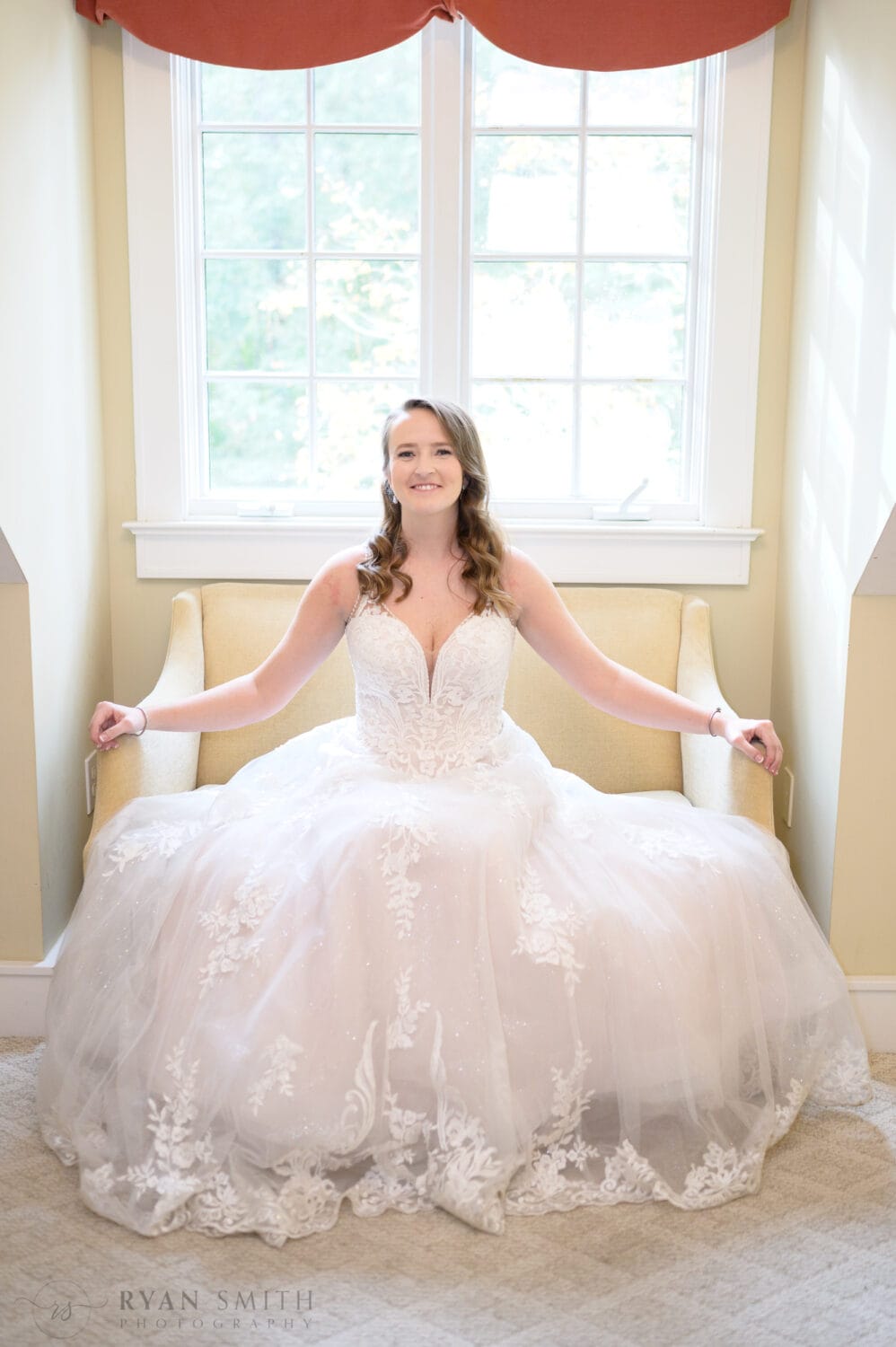 Bride sitting on the couch in the window light - Brookgreen Gardens