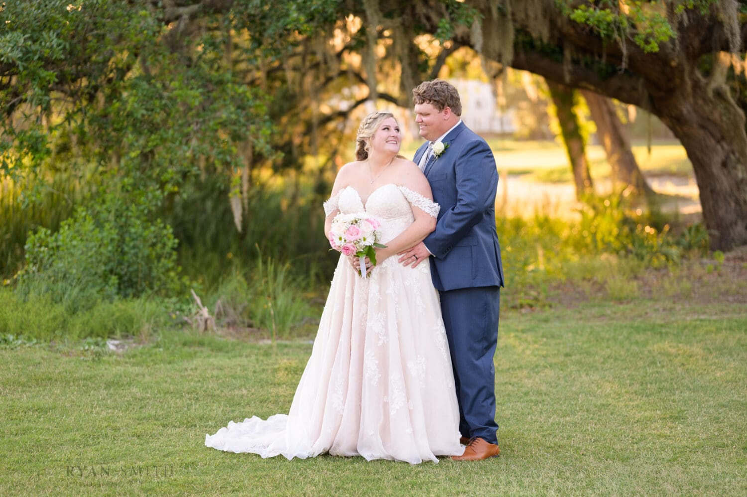 Groom hugging bride from behind looking into each others eyes - Pawleys Plantation