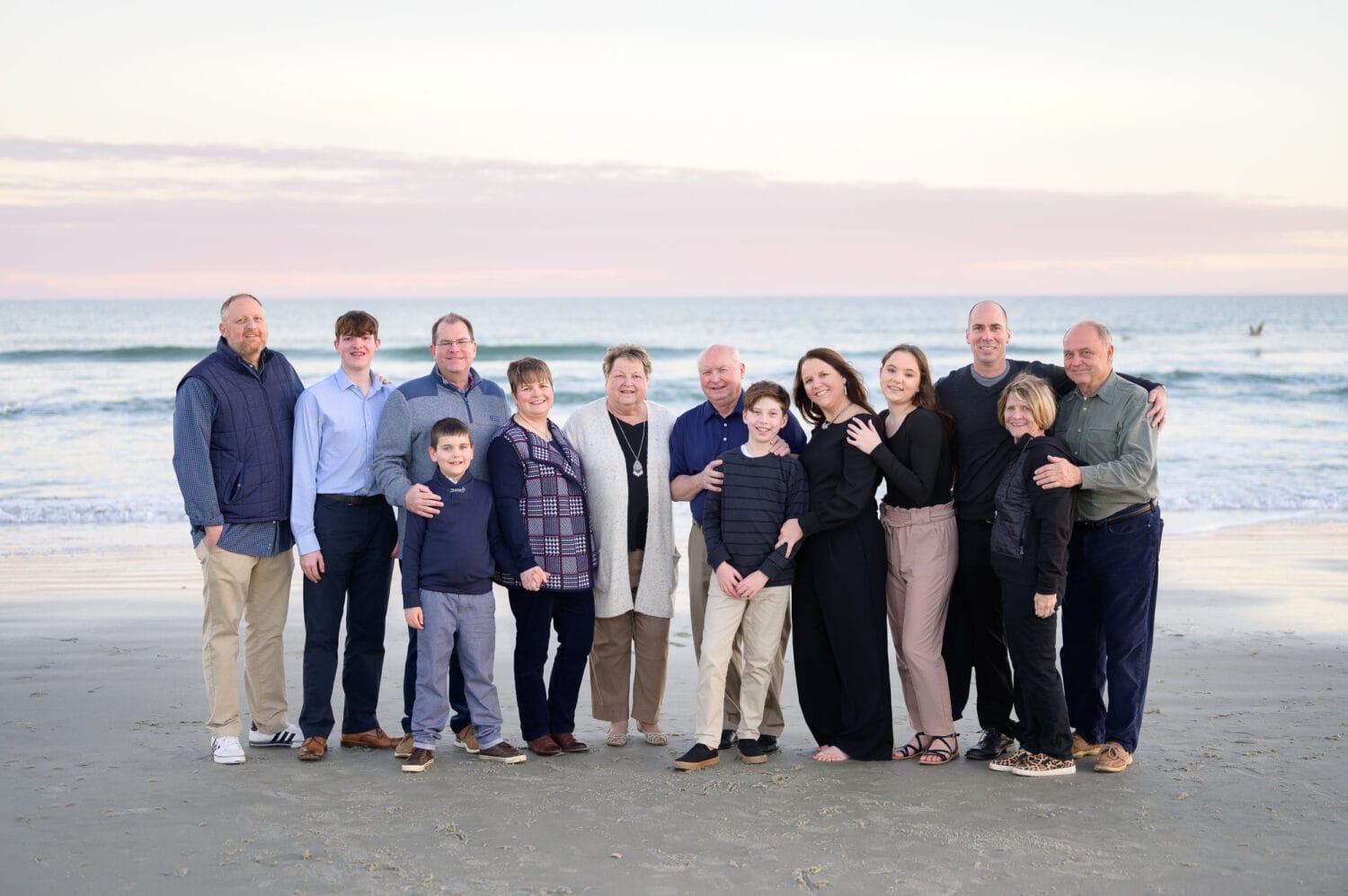 Large family with grandparents in front of the ocean during winter - Huntington Beach State Park